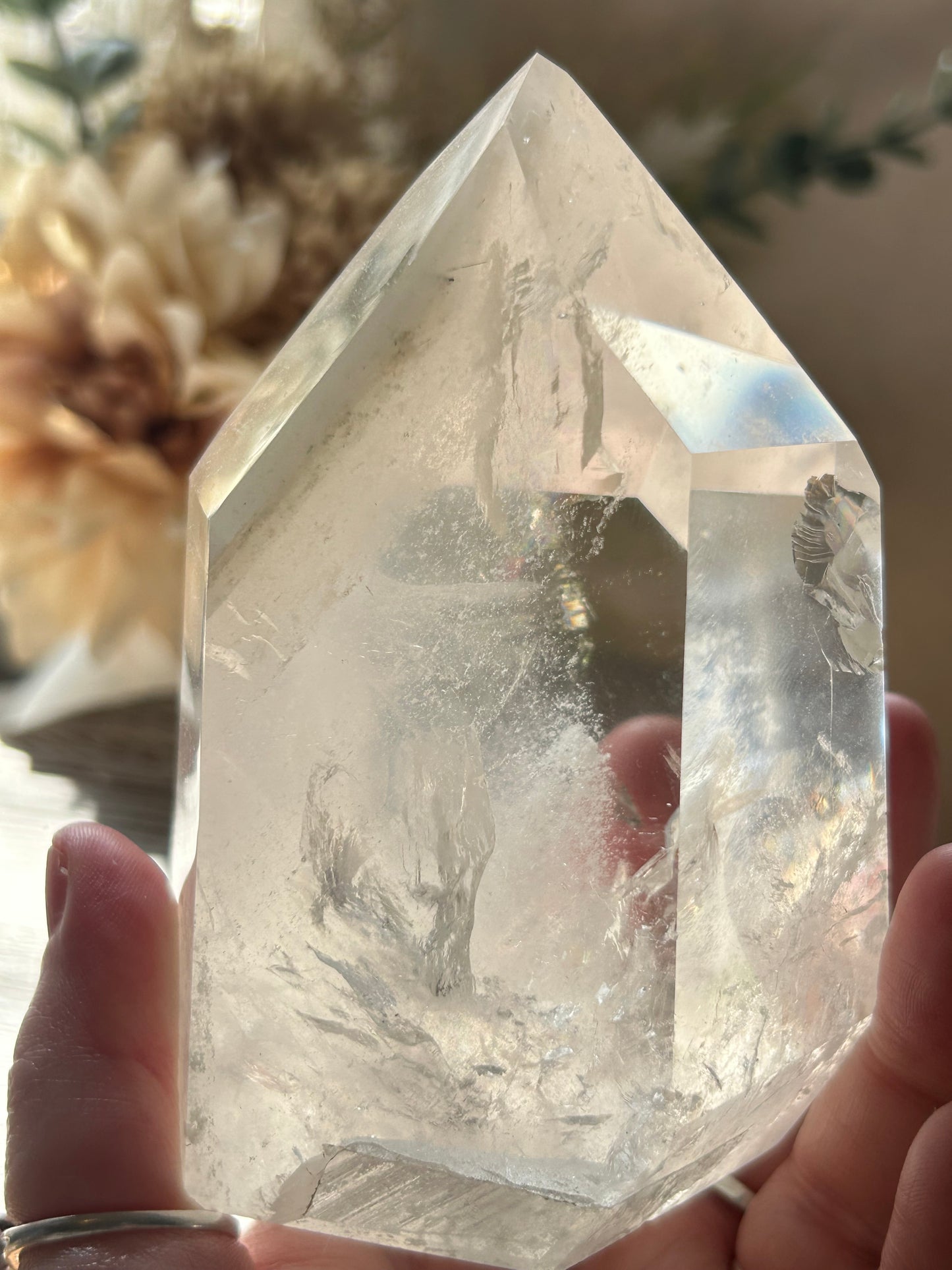 Clear crystal held by a hand with a blurred background