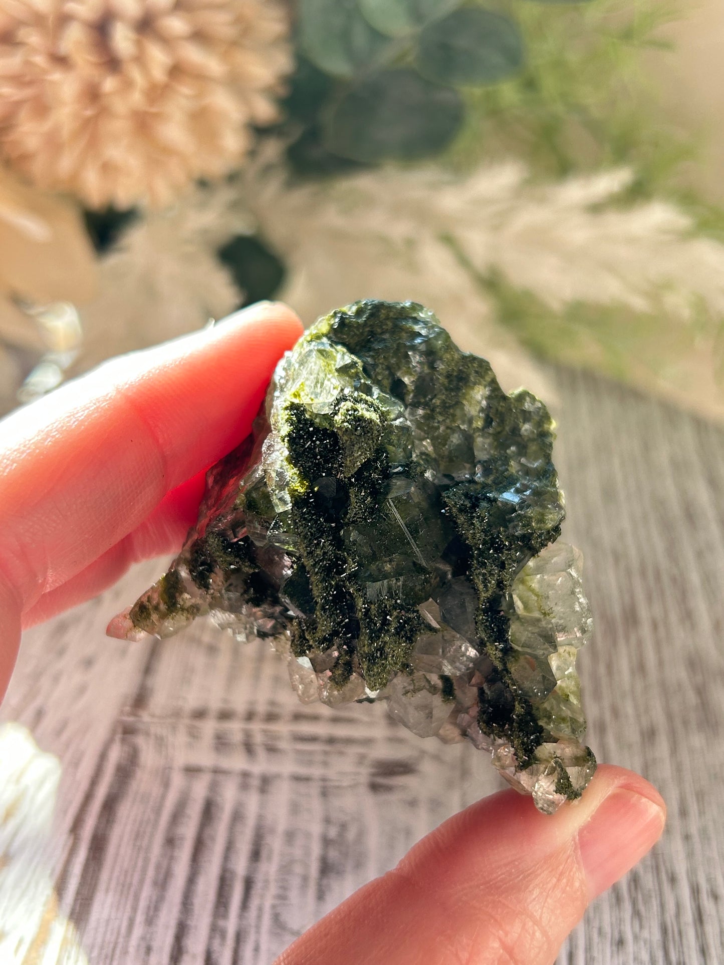 Hand holding a crystal rock with a blurred natural background