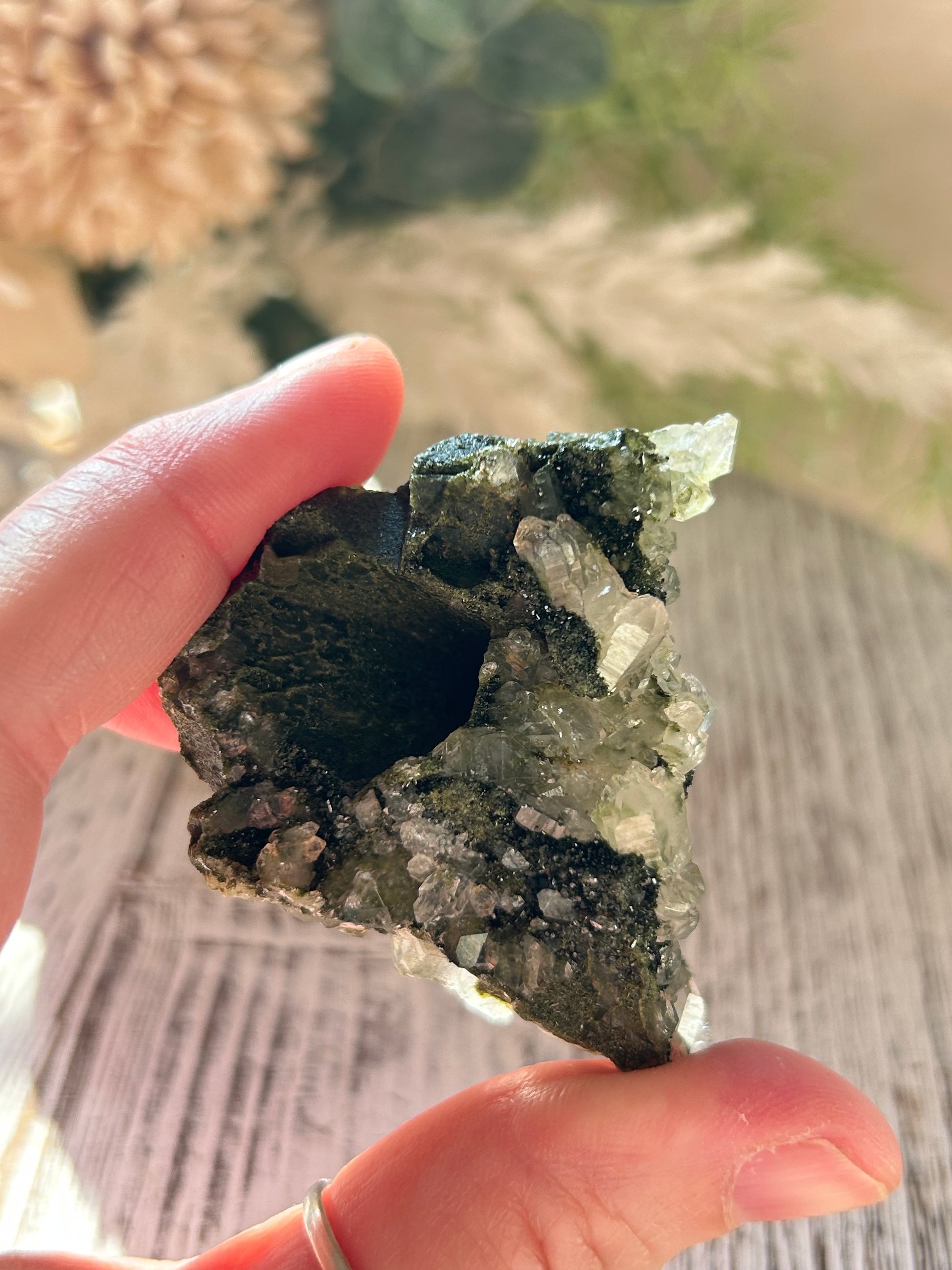 Hand holding a crystal rock with a blurred natural background