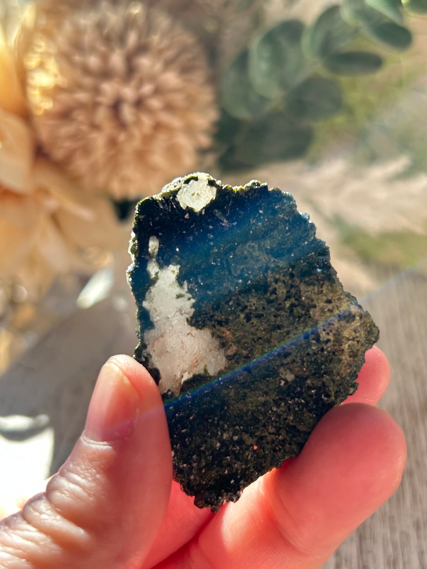 Person holding a blue and white mineral specimen with natural background