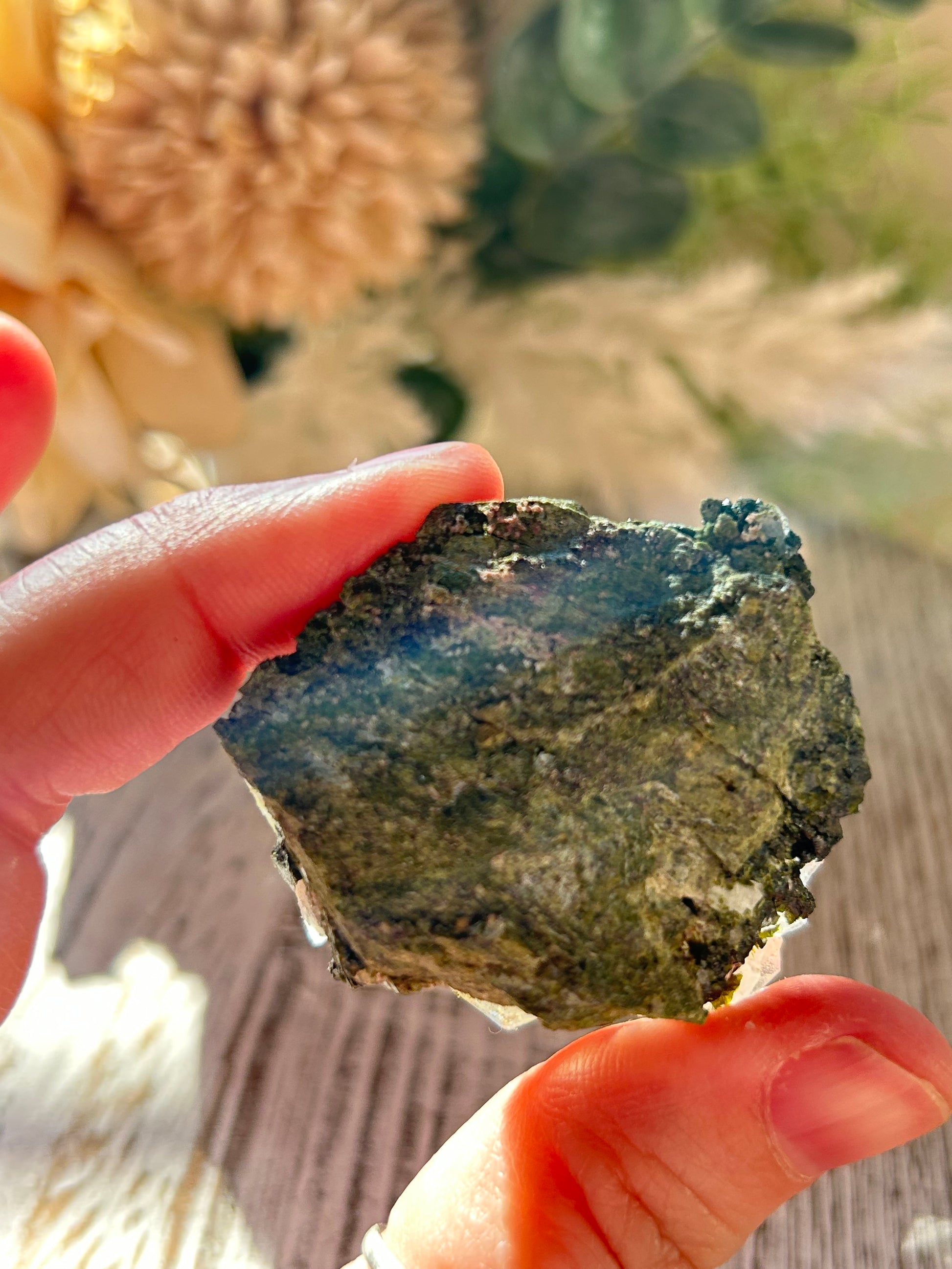 Hand holding a rough mineral stone with a blurred natural background