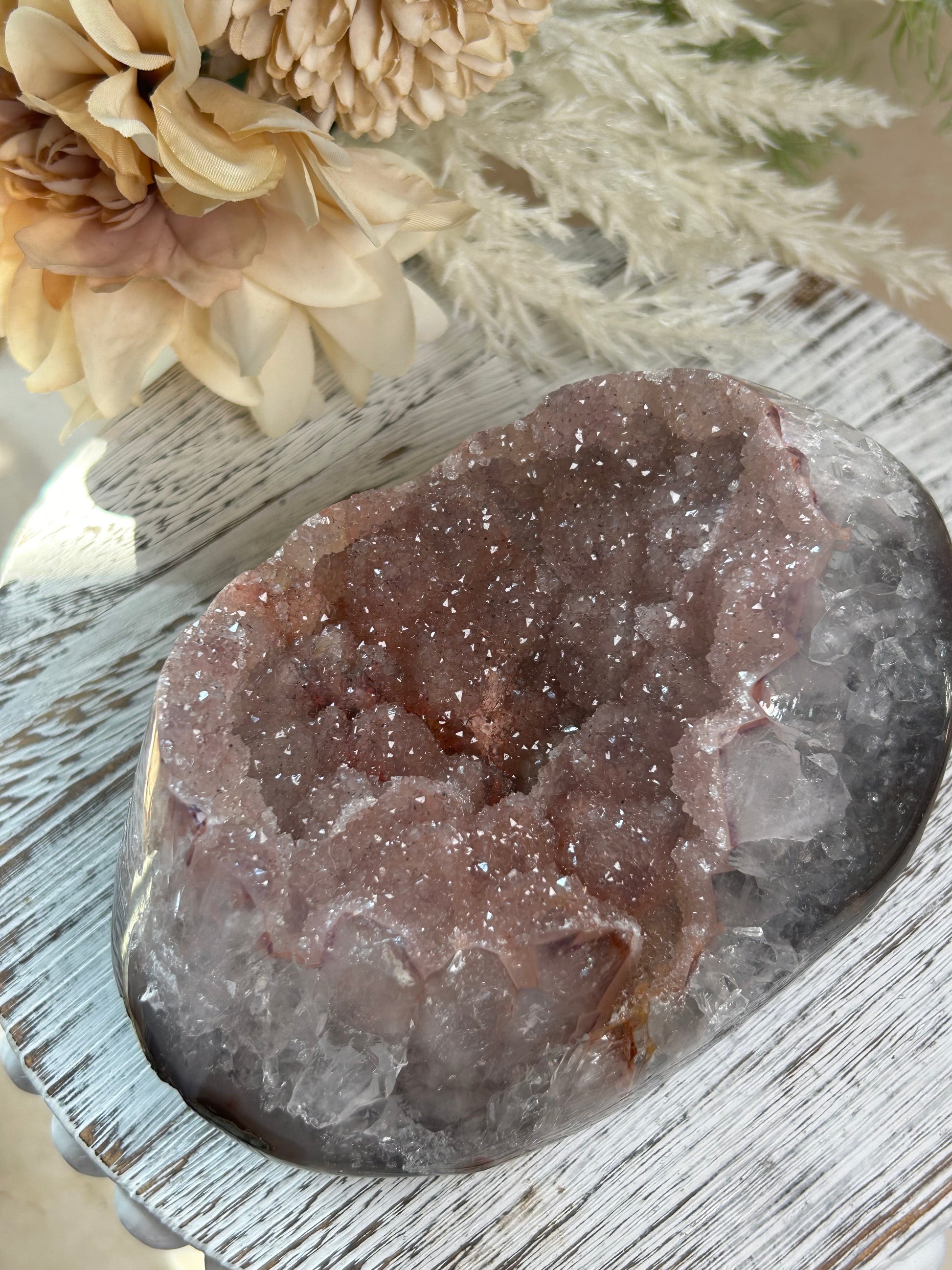 Crystal rock on a wooden surface with flowers in the background
