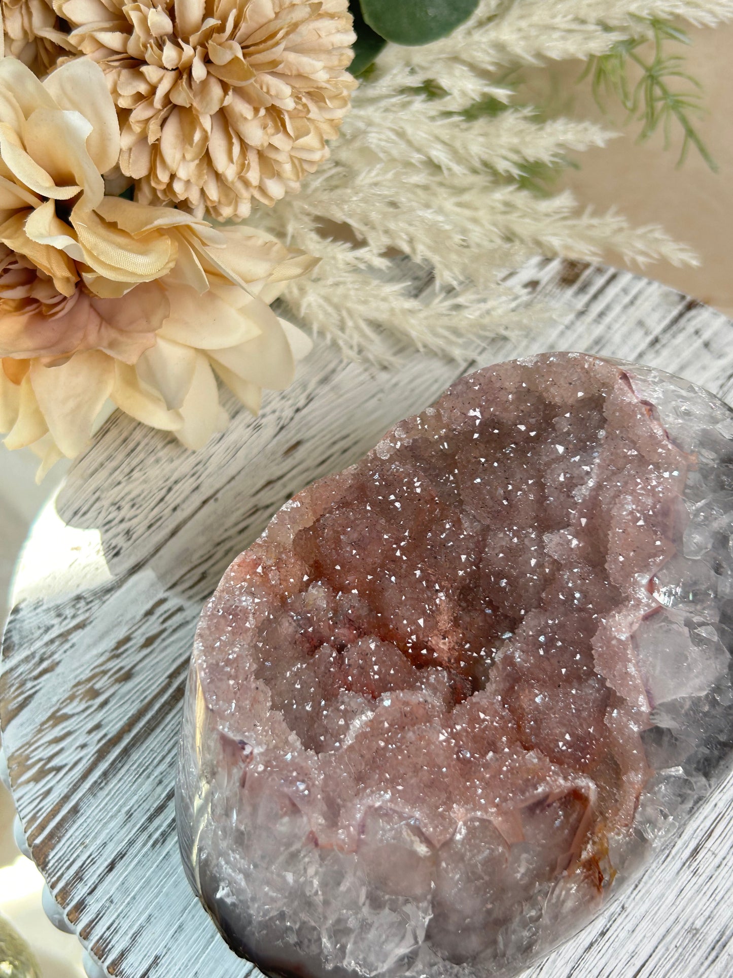 Close-up of a crystal rock with flowers on a textured surface