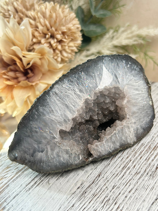 Rainbow Amethyst geode half with sparkling druzy centre, feathered quartz formations, and soft natural rainbow flashes.