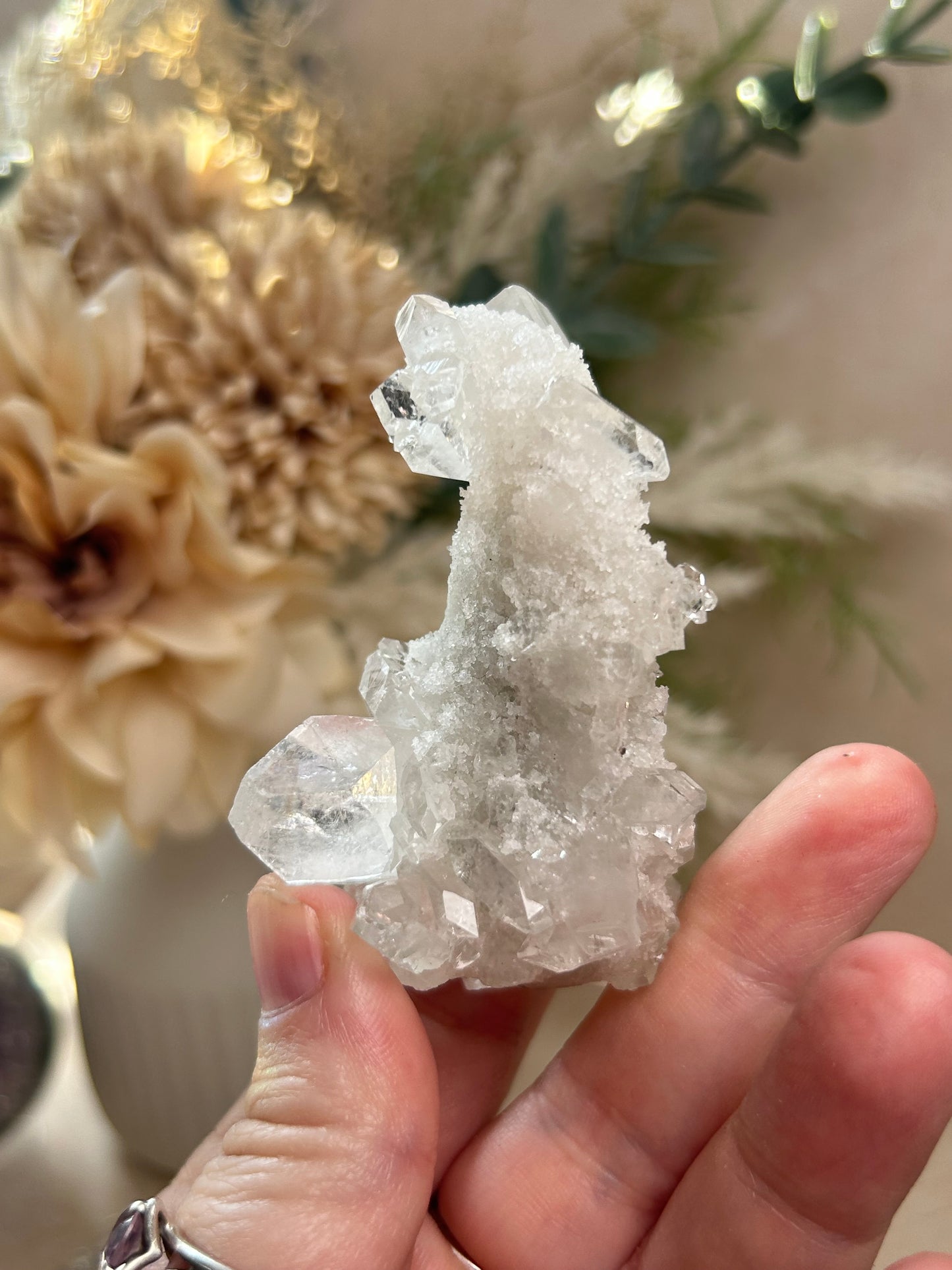 Hand holding a crystal cluster with a blurred natural background