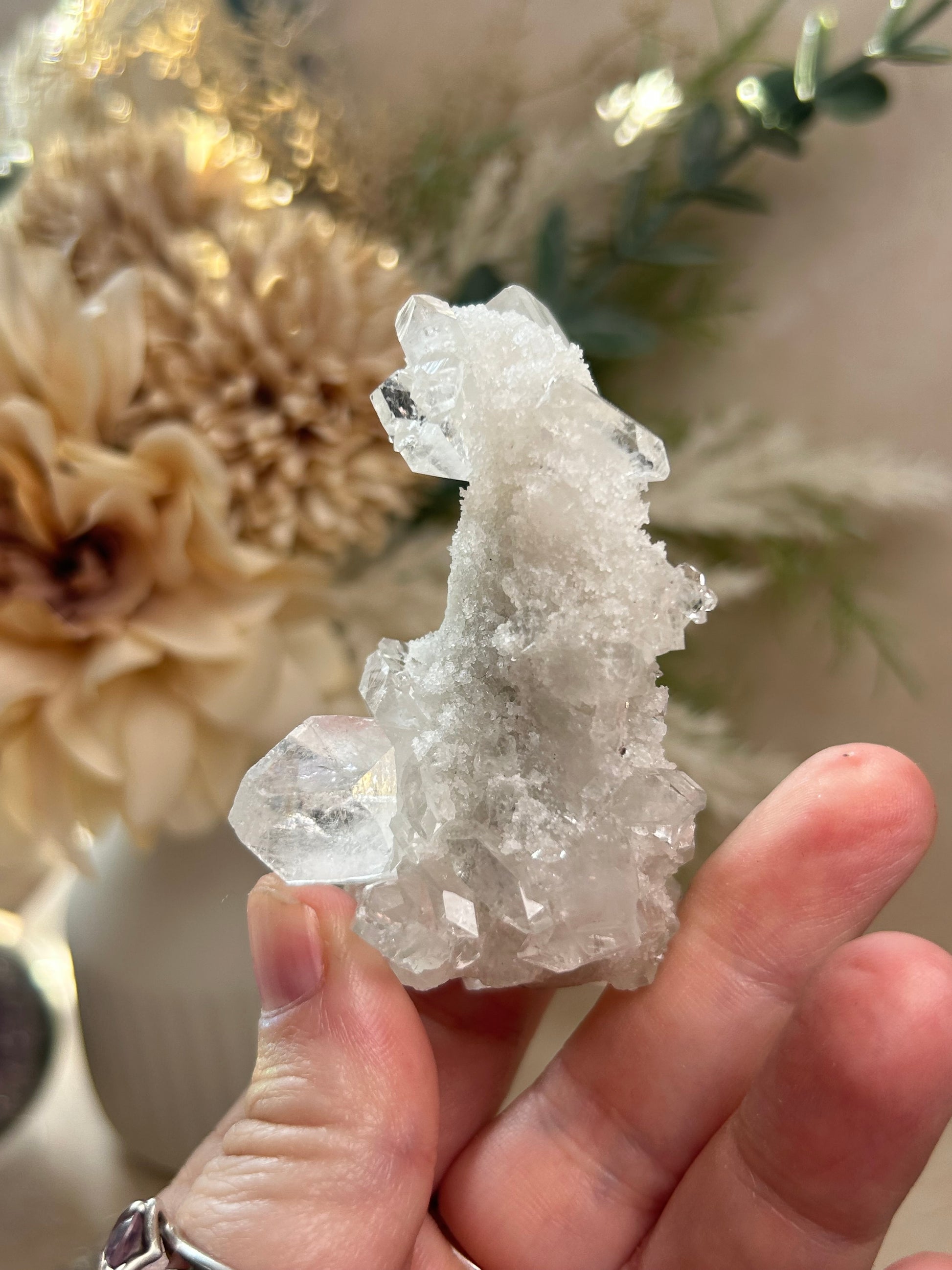 Hand holding a crystal cluster with a blurred natural background