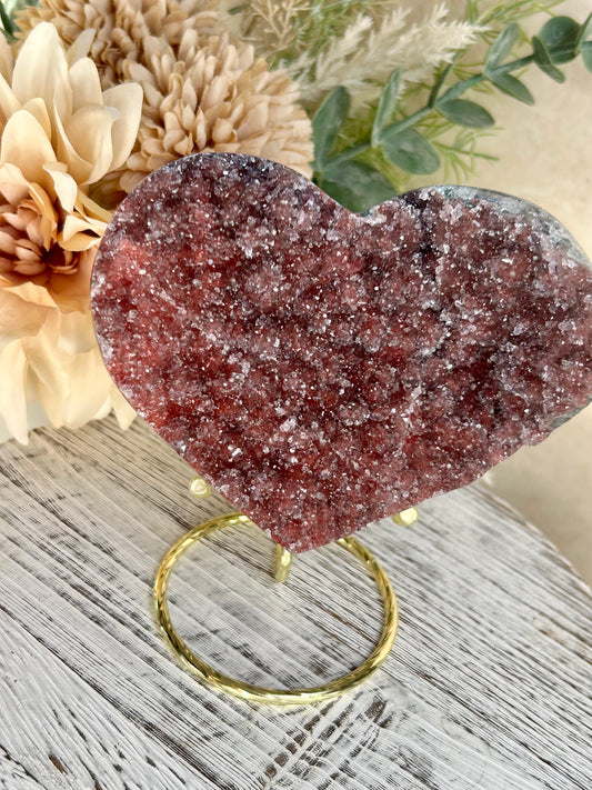 Heart-shaped crystal on a stand with decorative flowers in the background