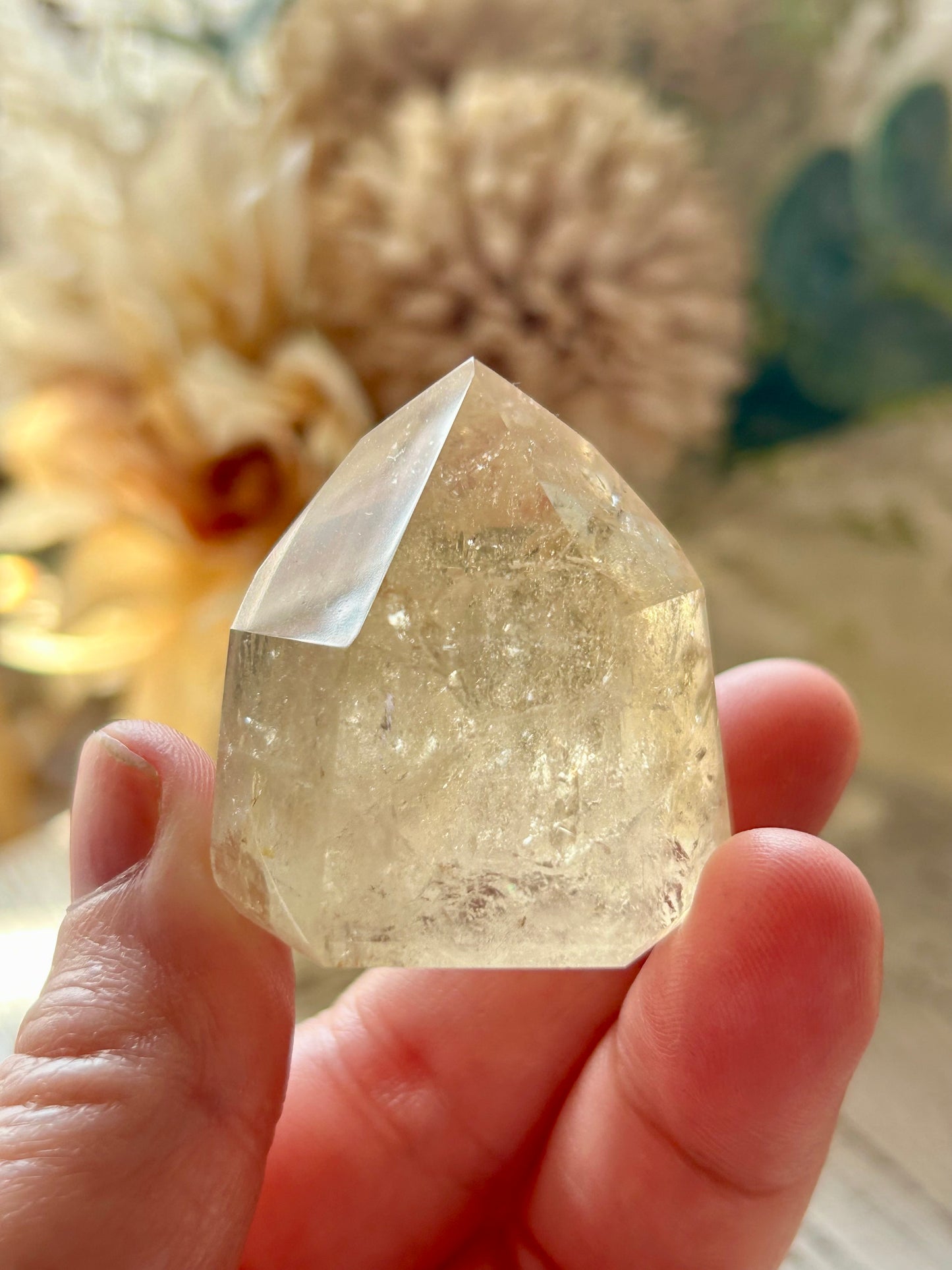 Clear crystal held in a hand with a blurred natural background