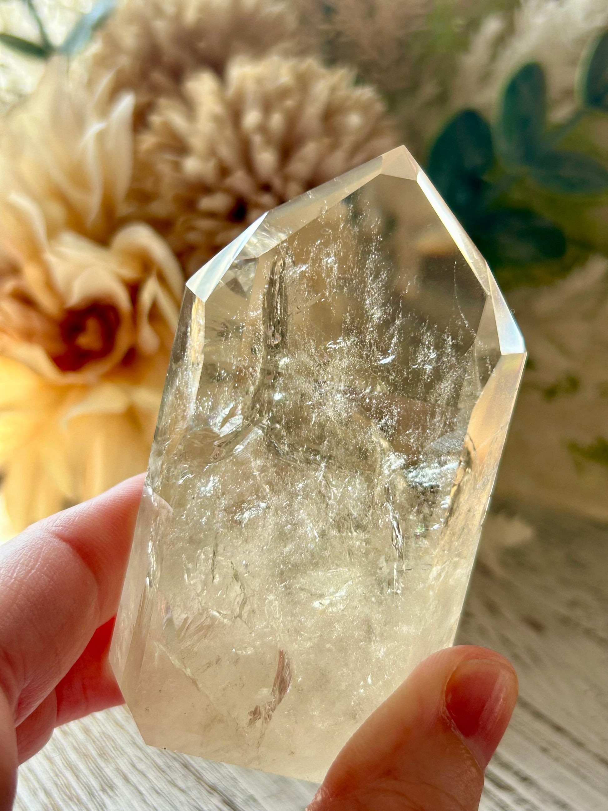 Clear crystal held in a hand with a blurred natural background