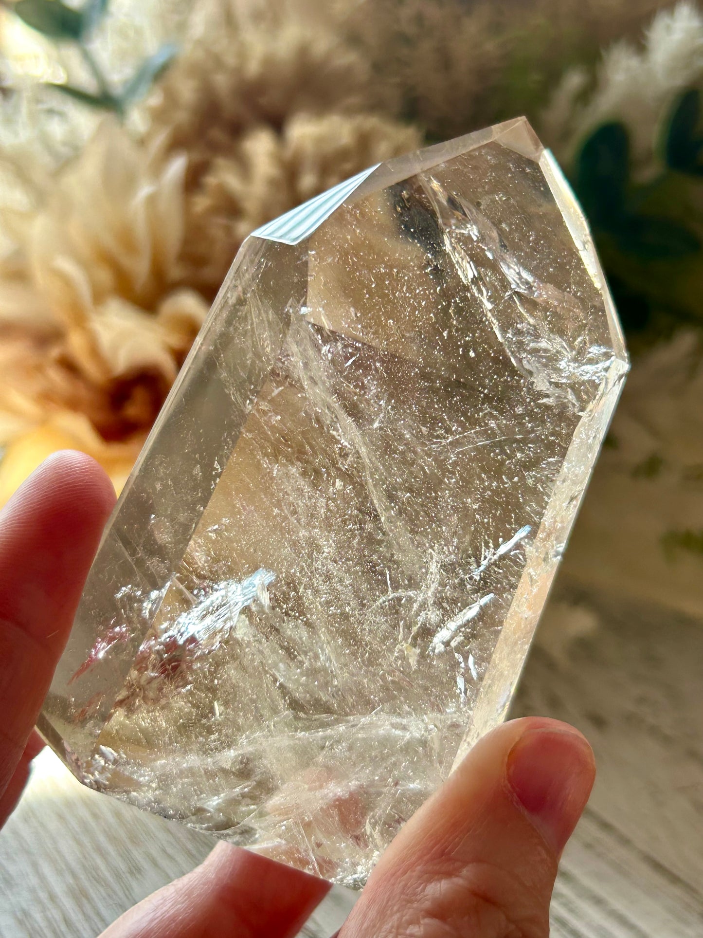 Clear crystal held by a hand with a blurred natural background