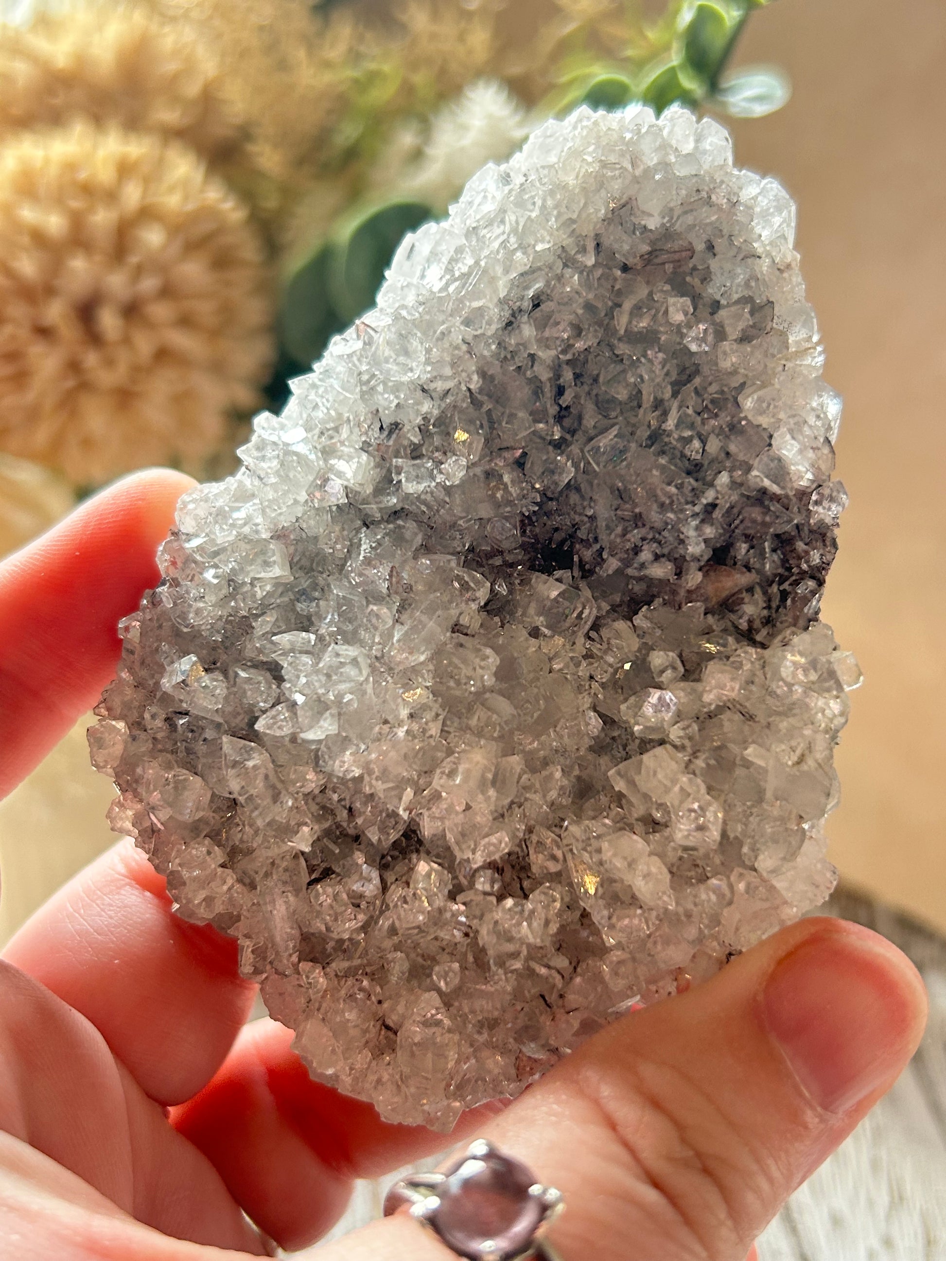 Hand holding a crystal rock with a blurred natural background