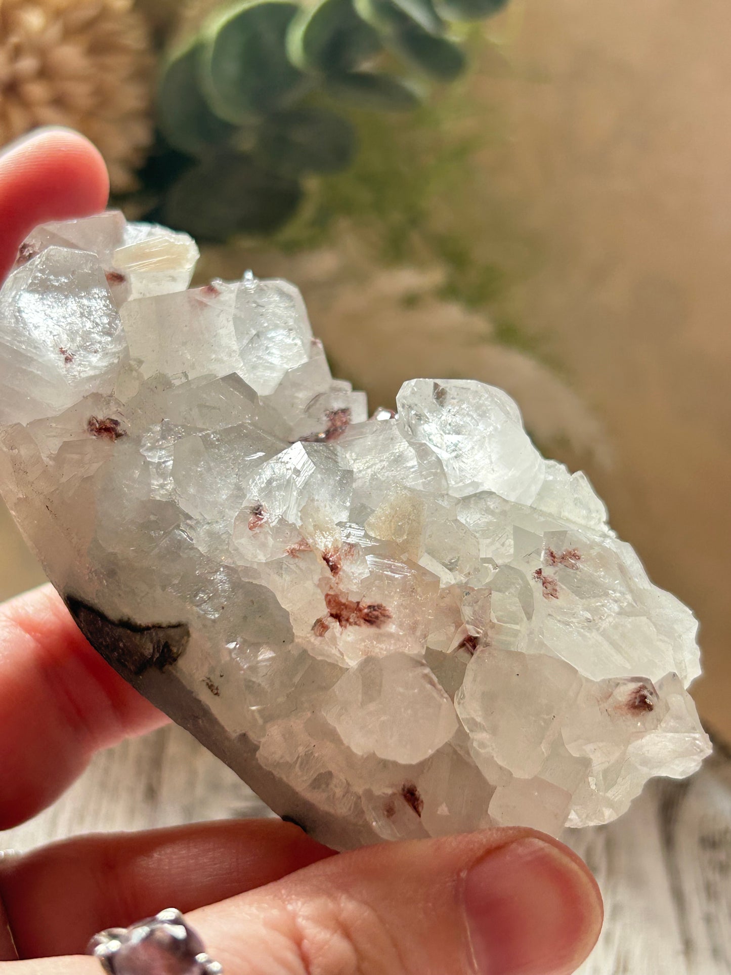 Clear crystal rock held by a hand with a blurred natural background