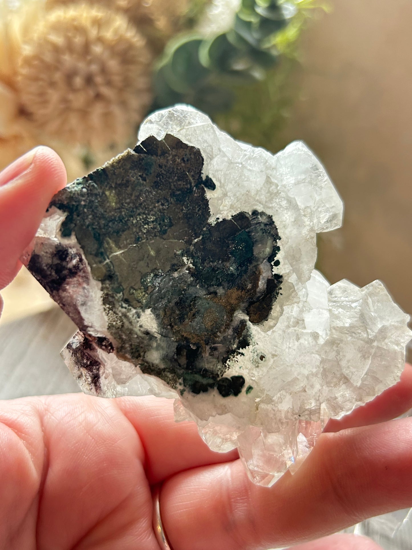 Person holding a crystal with black and green mineral inclusions