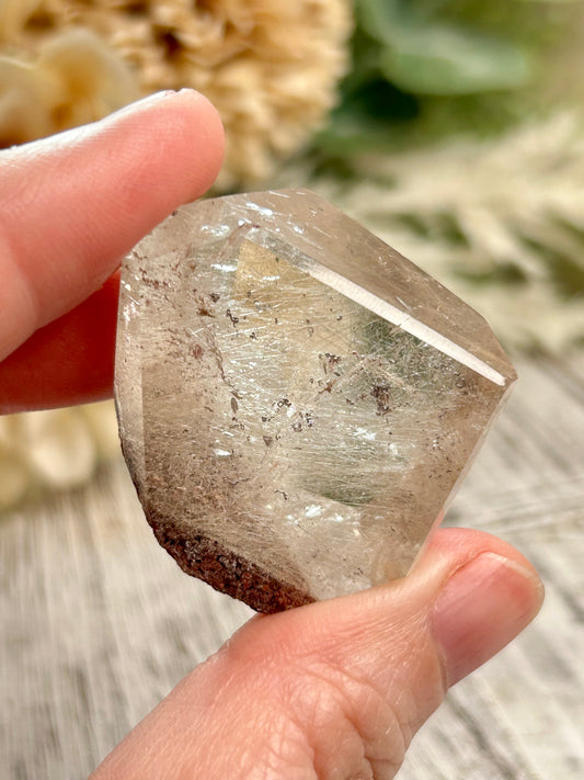 Hand holding a clear crystal with natural background