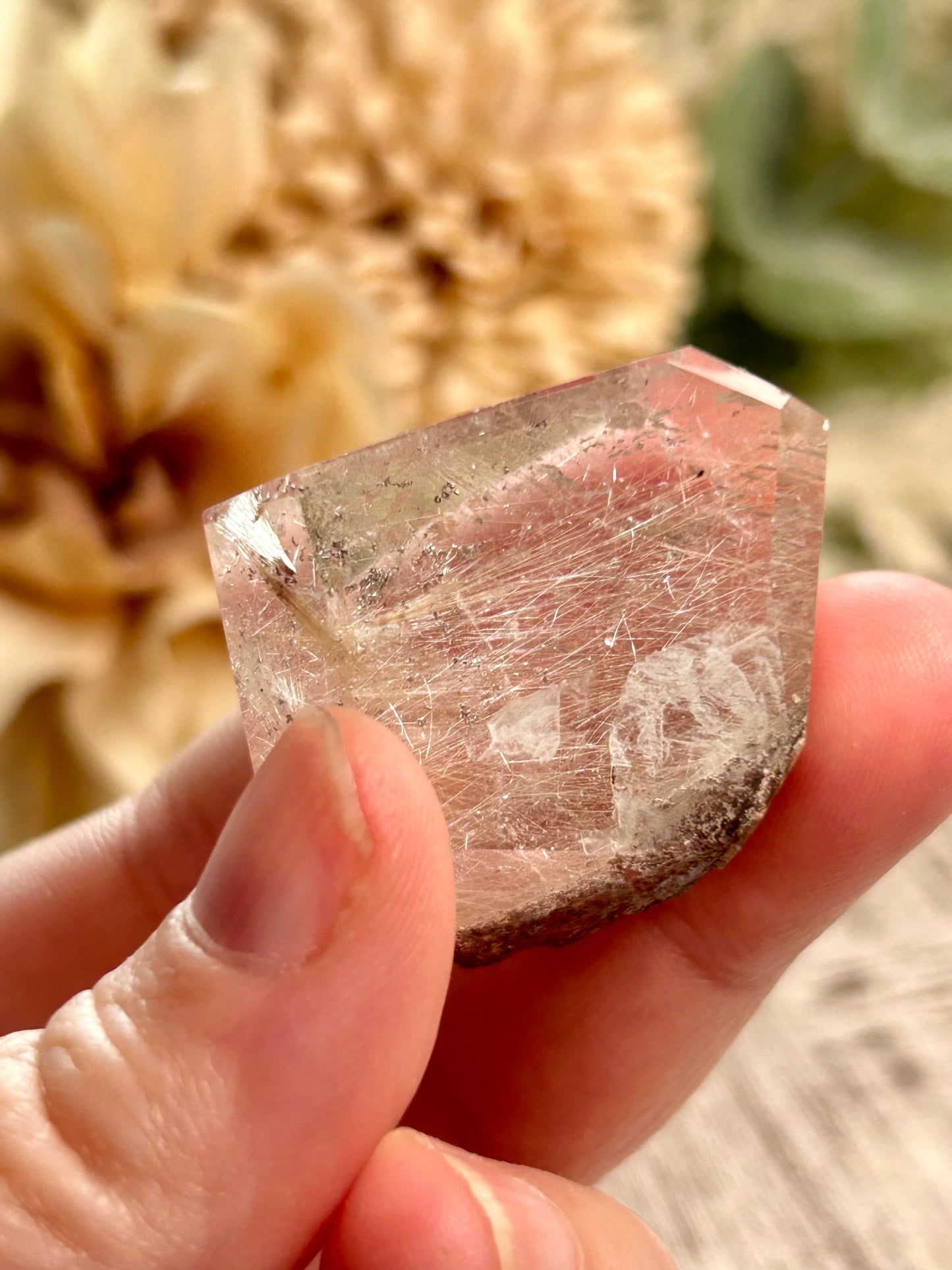 Hand holding a rough crystal with blurred natural background