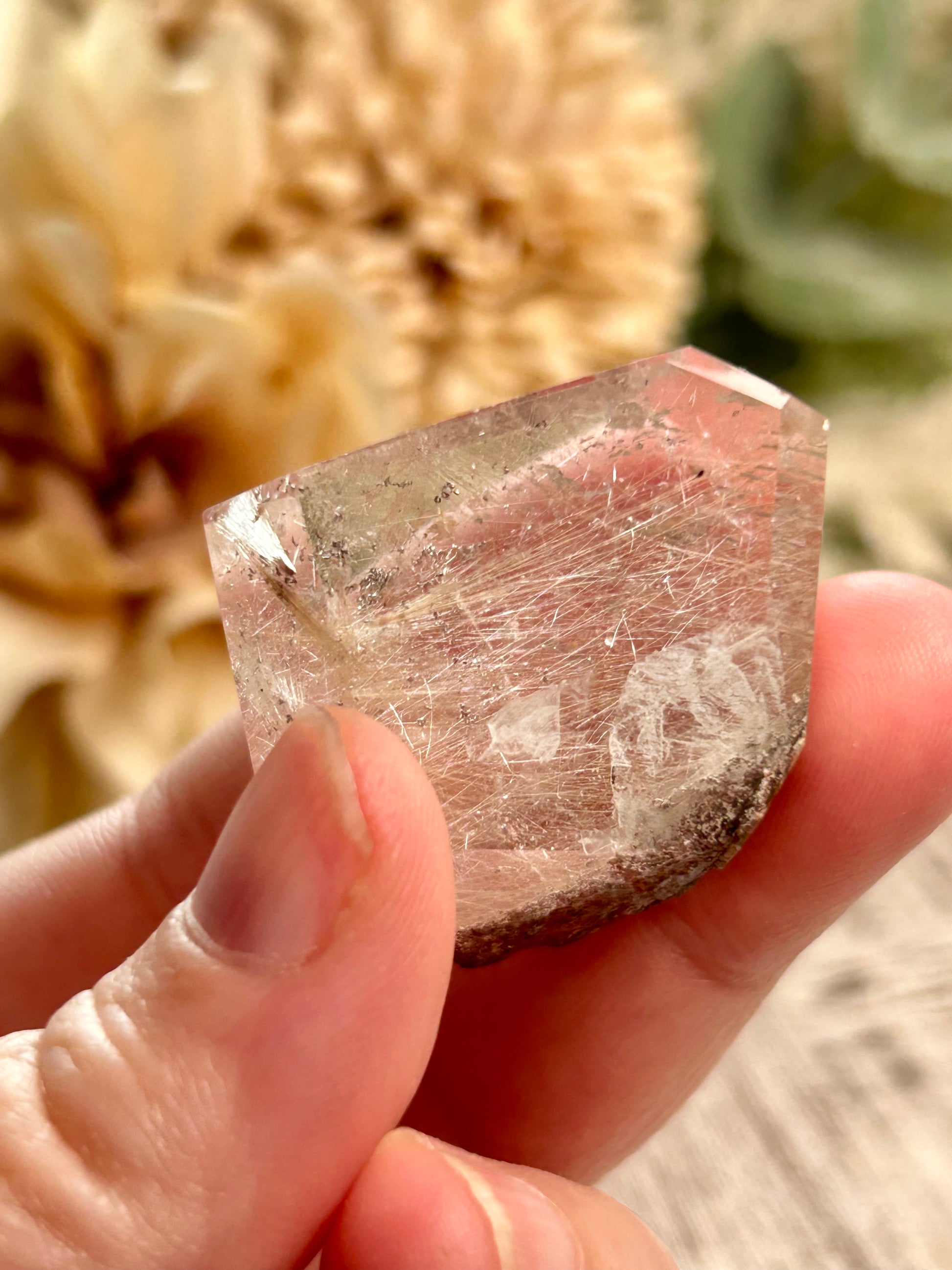 Hand holding a rough crystal with blurred natural background