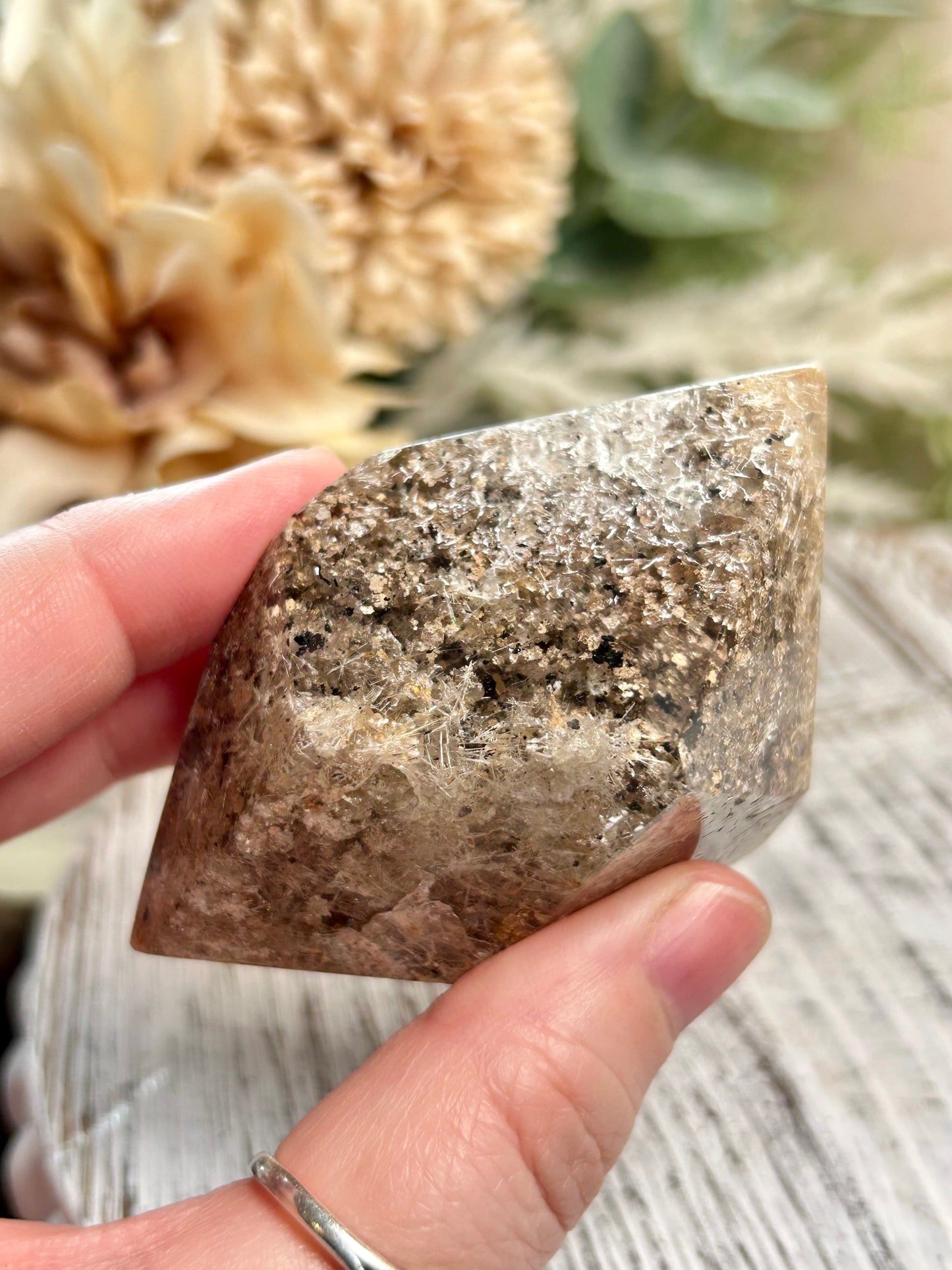 Hand holding a rough crystal with a blurred natural background