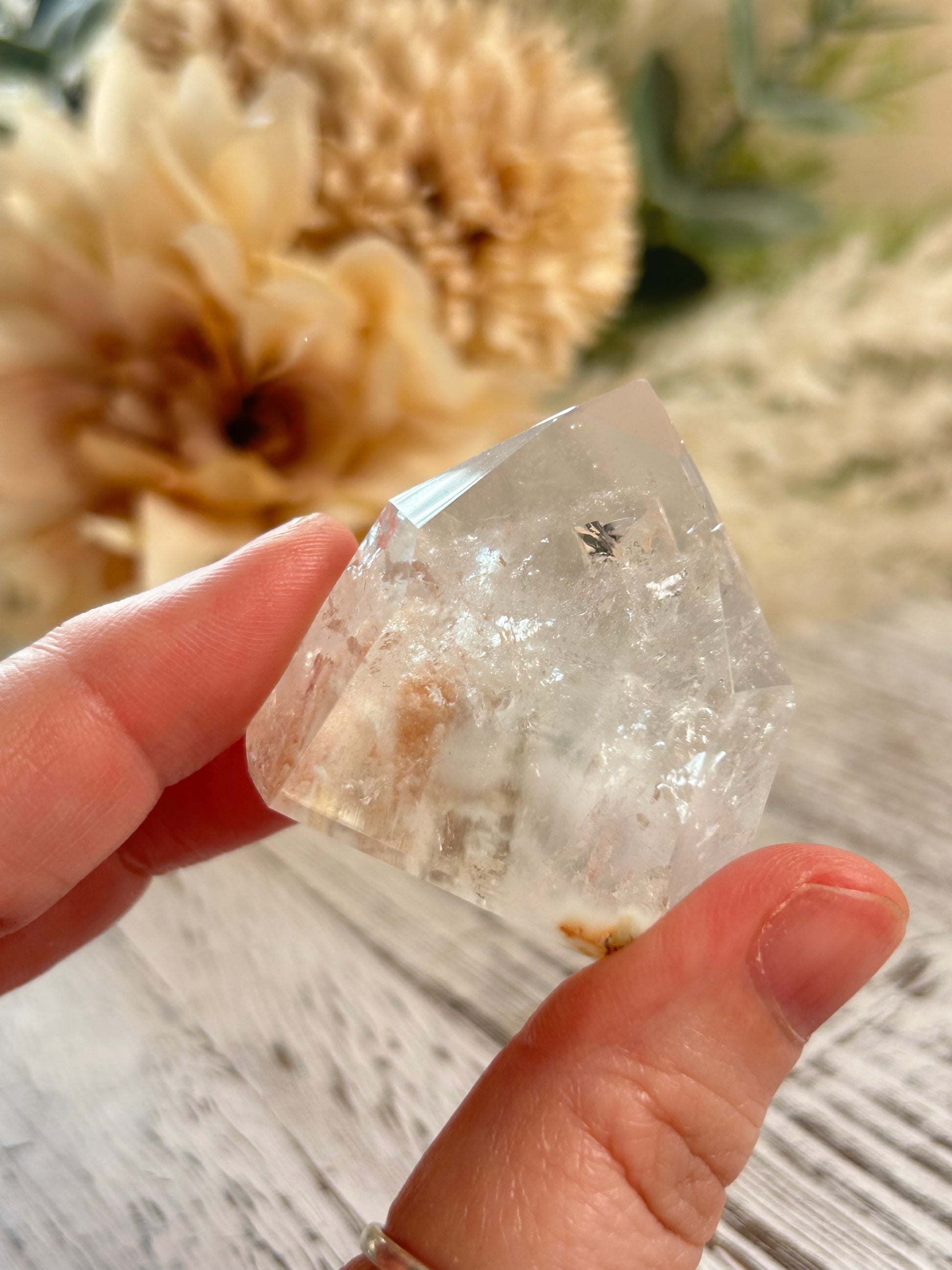 Hand holding a clear crystal with a blurred natural background