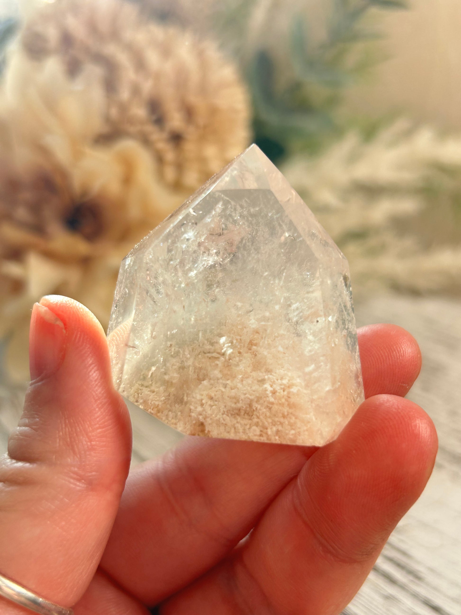 Hand holding a clear crystal with a blurred natural background