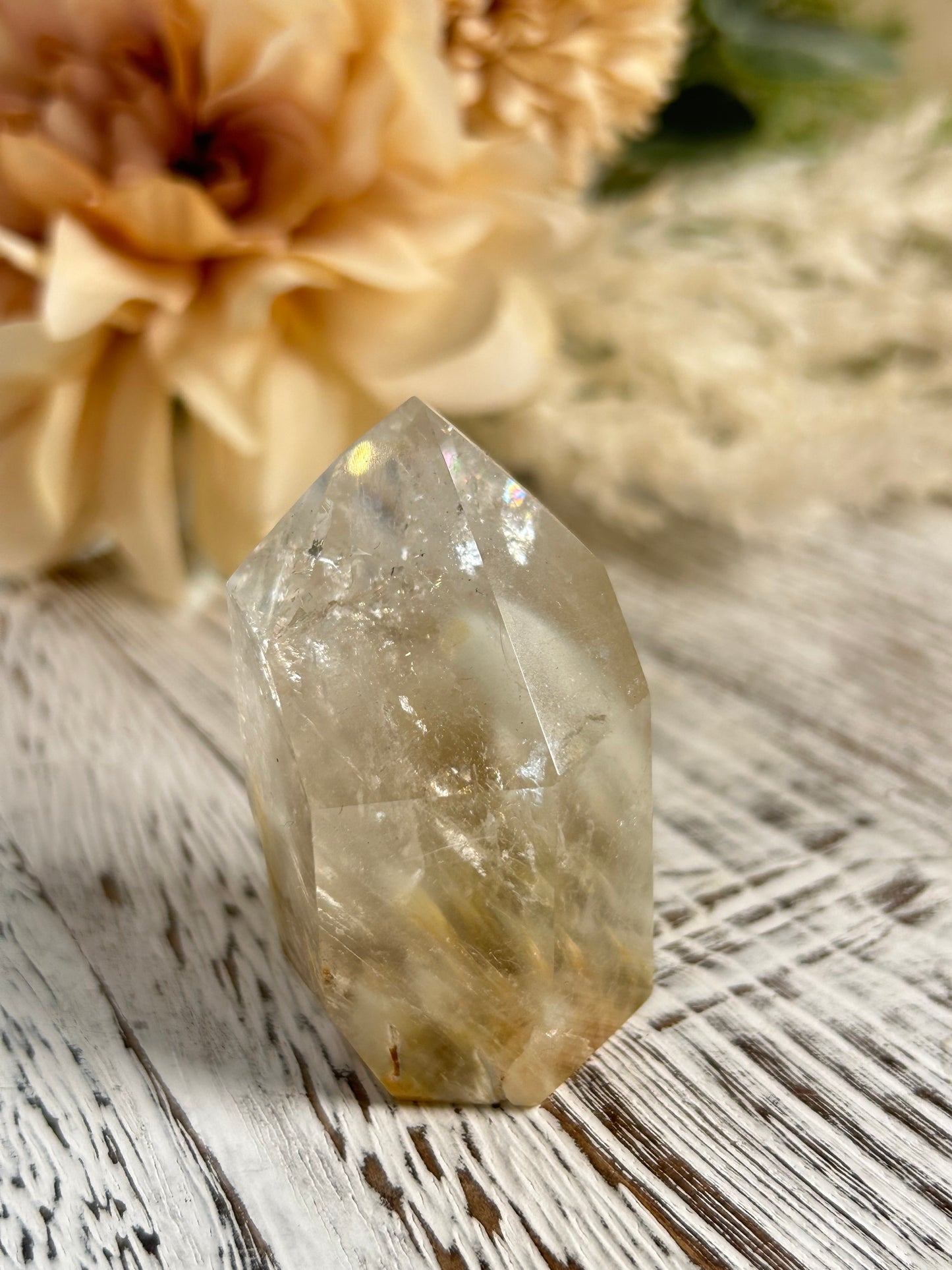Clear crystal on a textured surface with dried flowers in the background