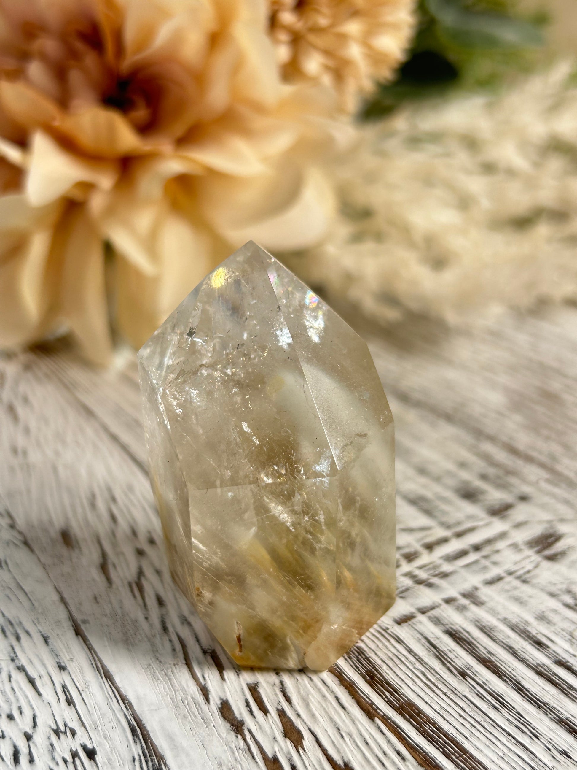 Clear crystal on a textured surface with dried flowers in the background