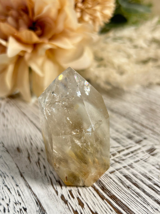 Clear crystal on a textured surface with dried flowers in the background