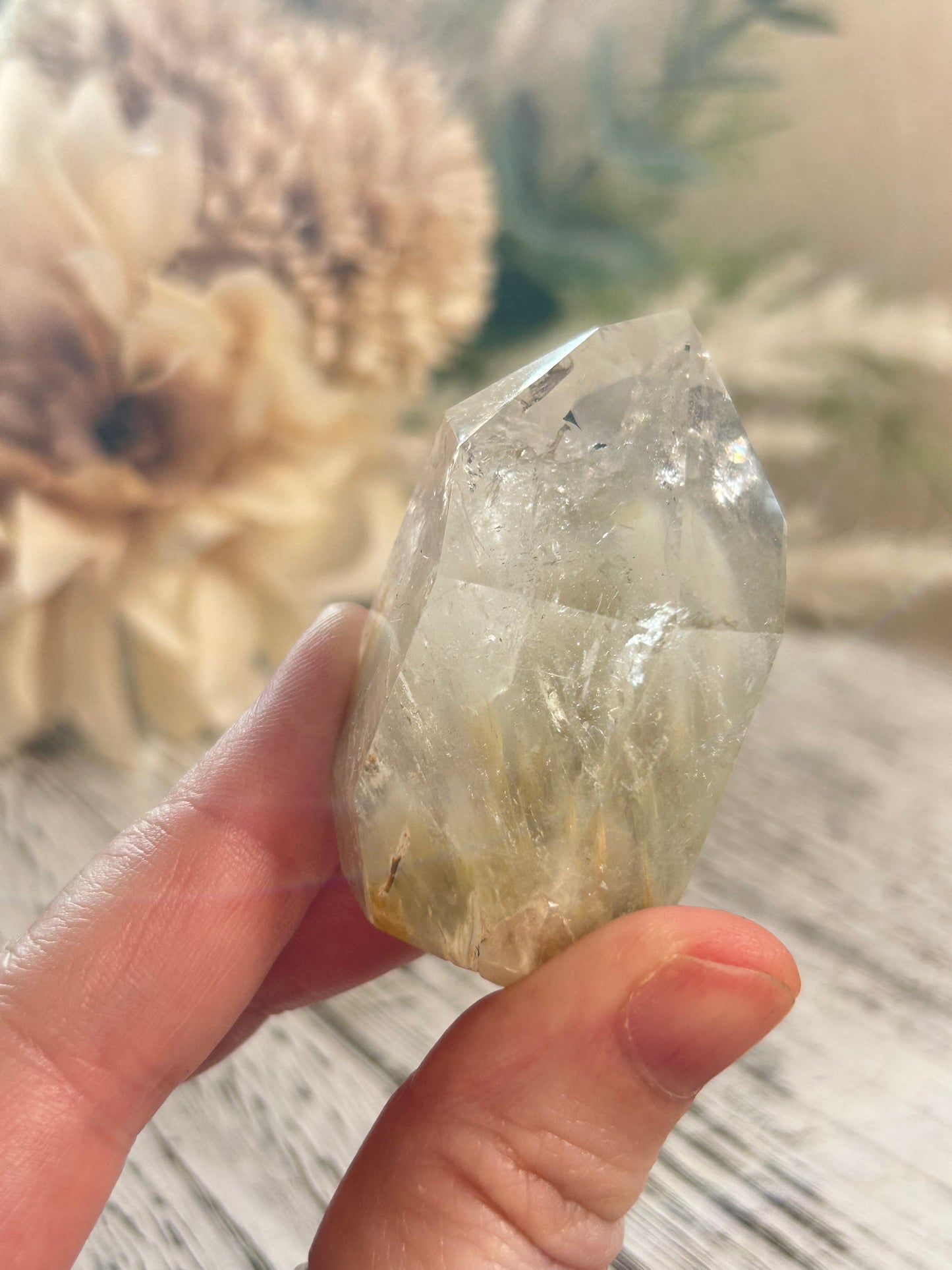 Hand holding a clear crystal with a blurred natural background