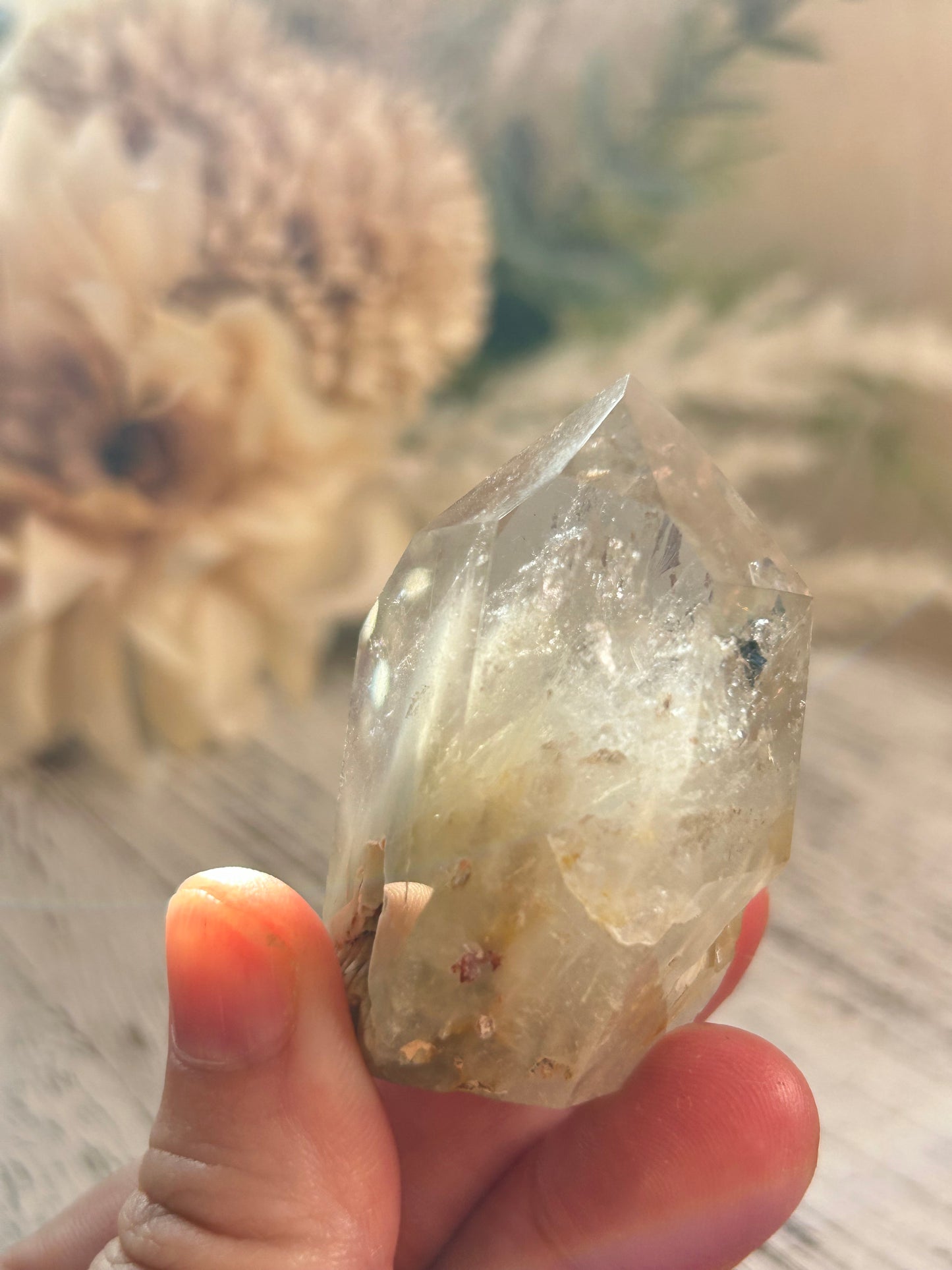 Clear crystal held in a hand with a natural background