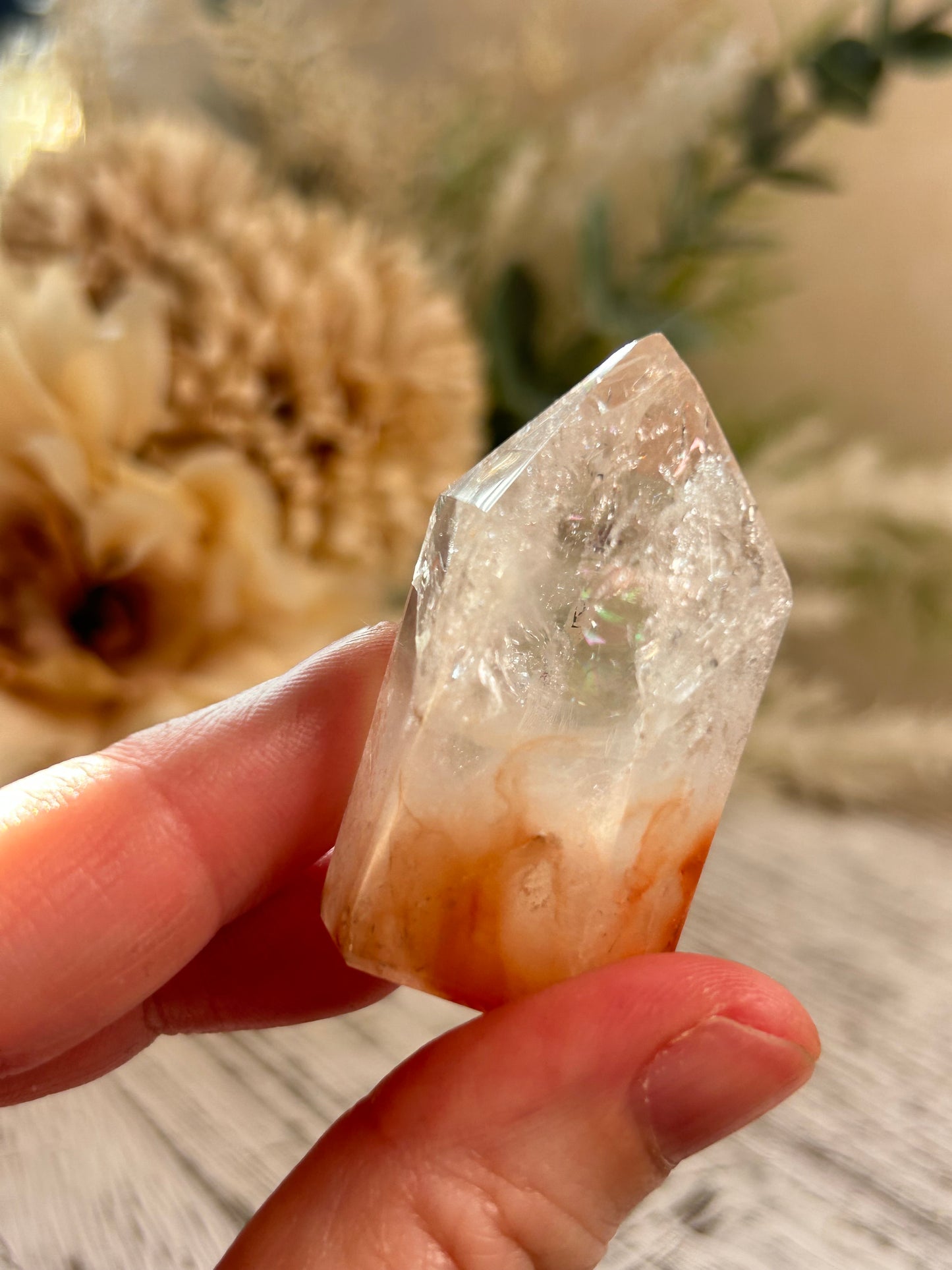 Hand holding a clear crystal with a blurred natural background