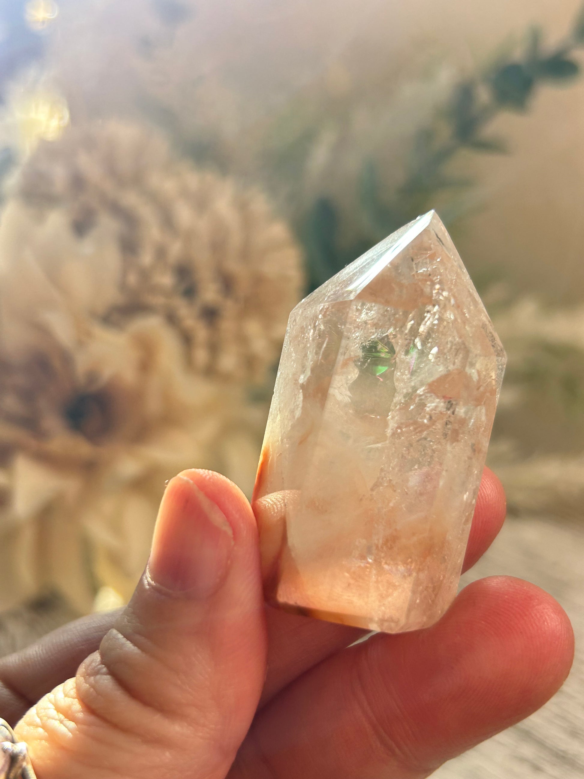 Hand holding a crystal against a blurred natural background