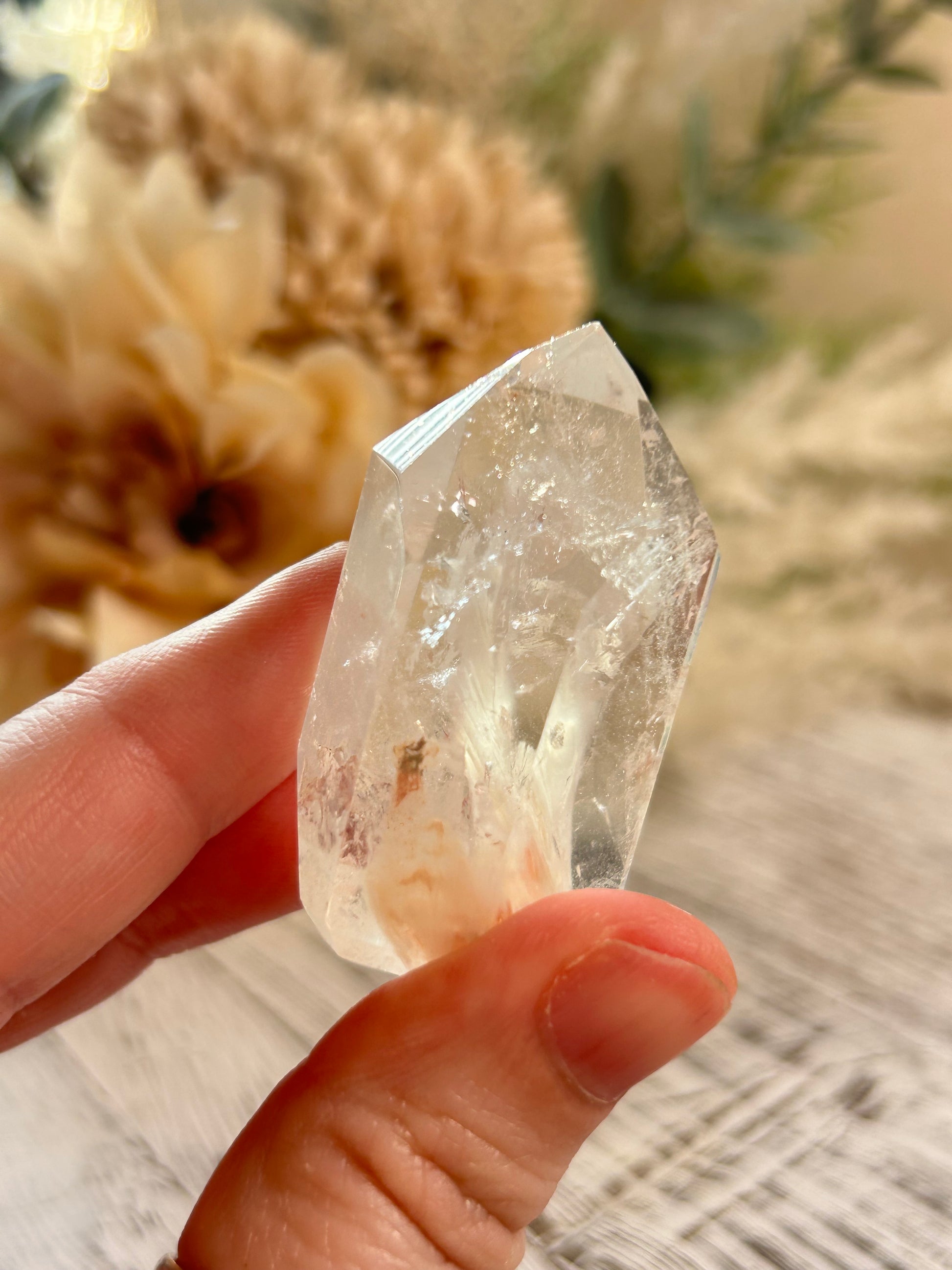 Hand holding a clear crystal with a blurred natural background