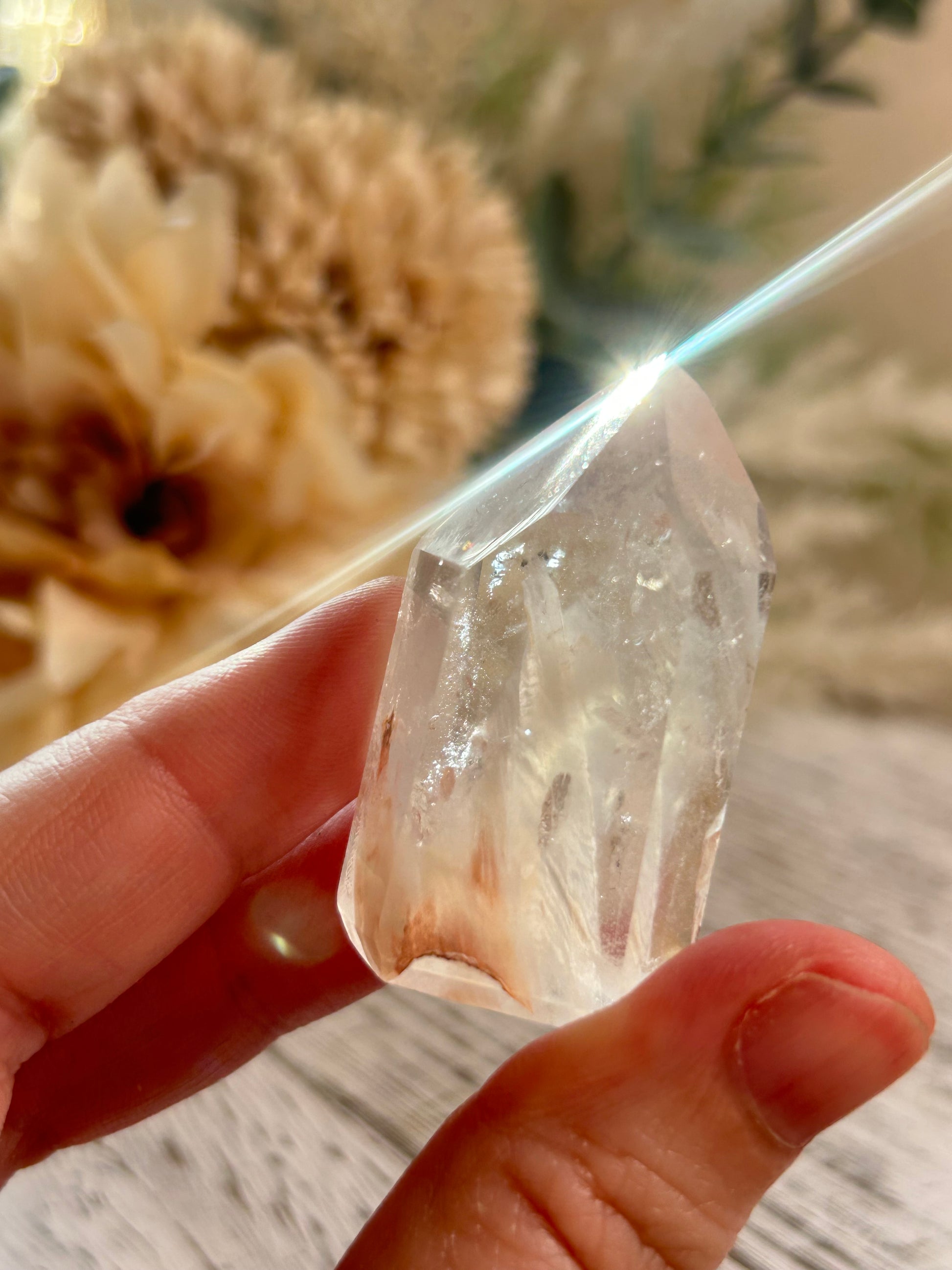 Clear crystal held in a hand with a blurred natural background