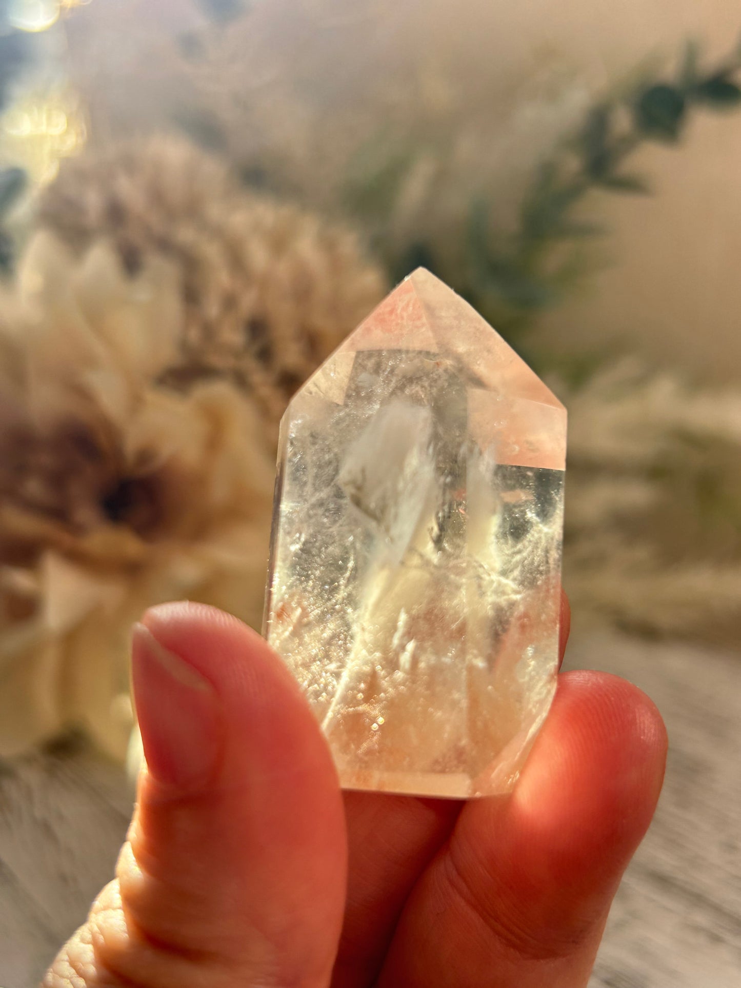 Hand holding a clear crystal with a blurred natural background