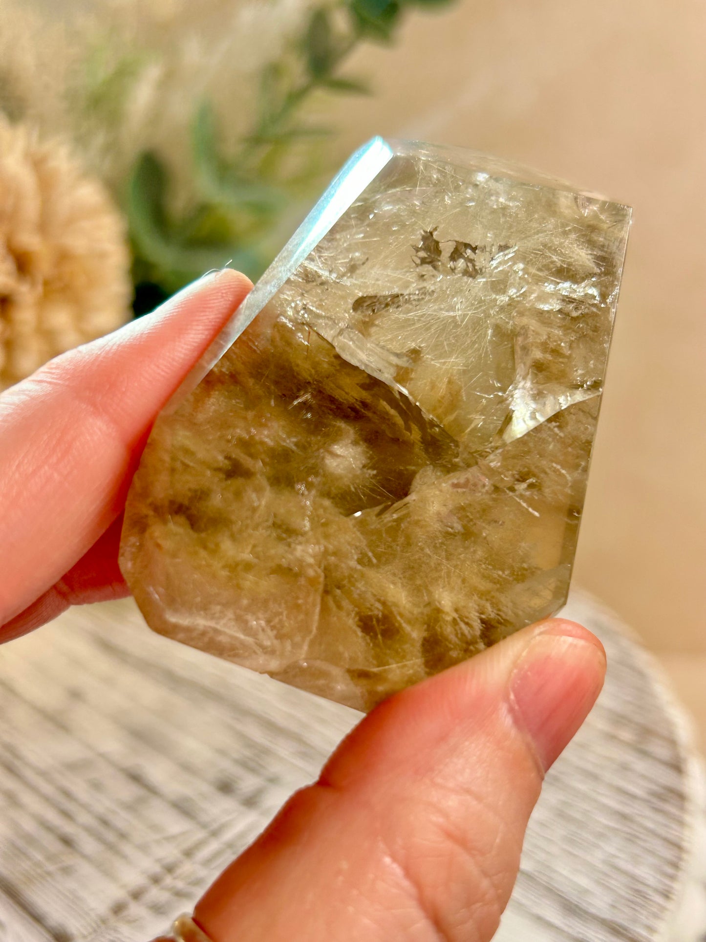 Clear crystal held by a hand with a blurred natural background