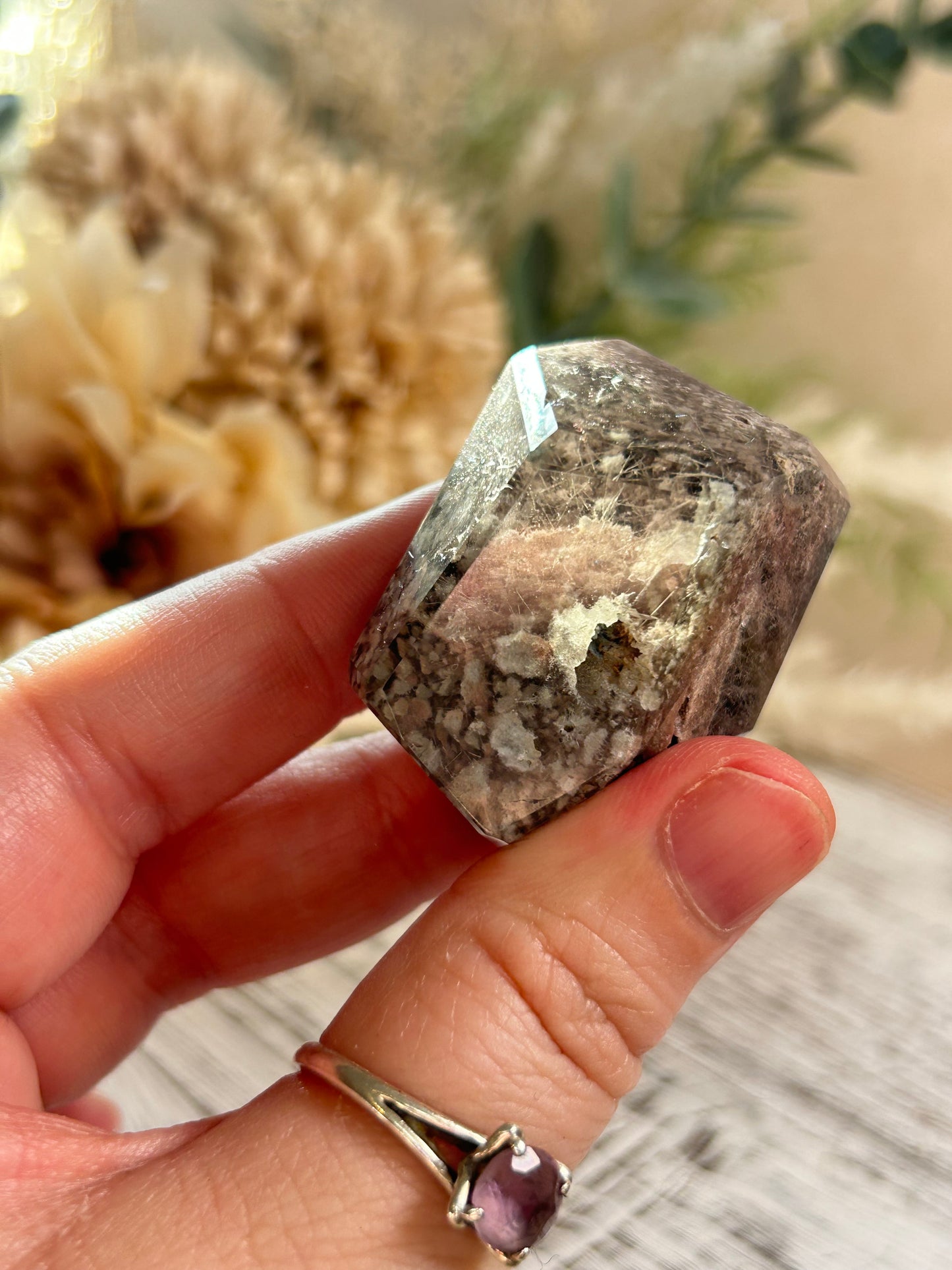 Hand holding a rough crystal with a blurred natural background