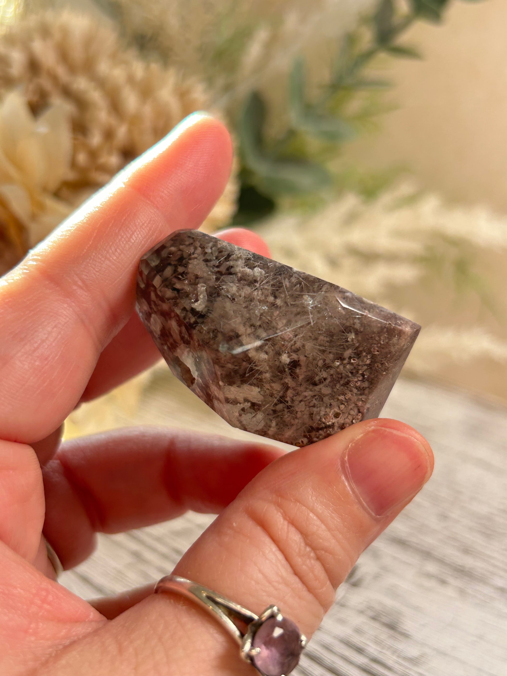 Hand holding a rough stone with a blurred natural background