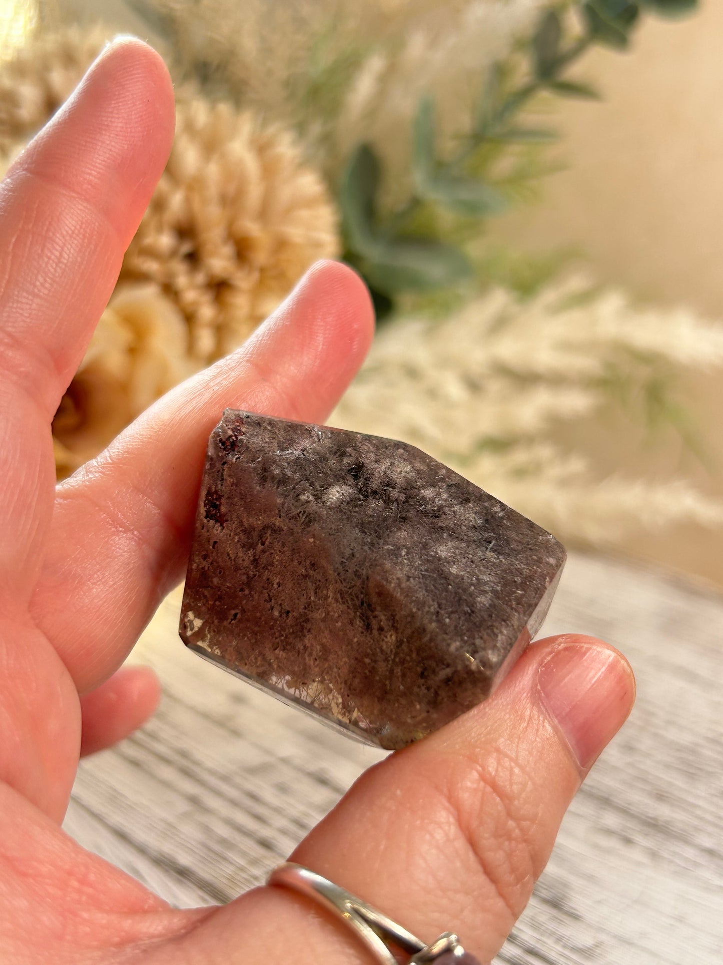 Hand holding a rough stone with a blurred natural background