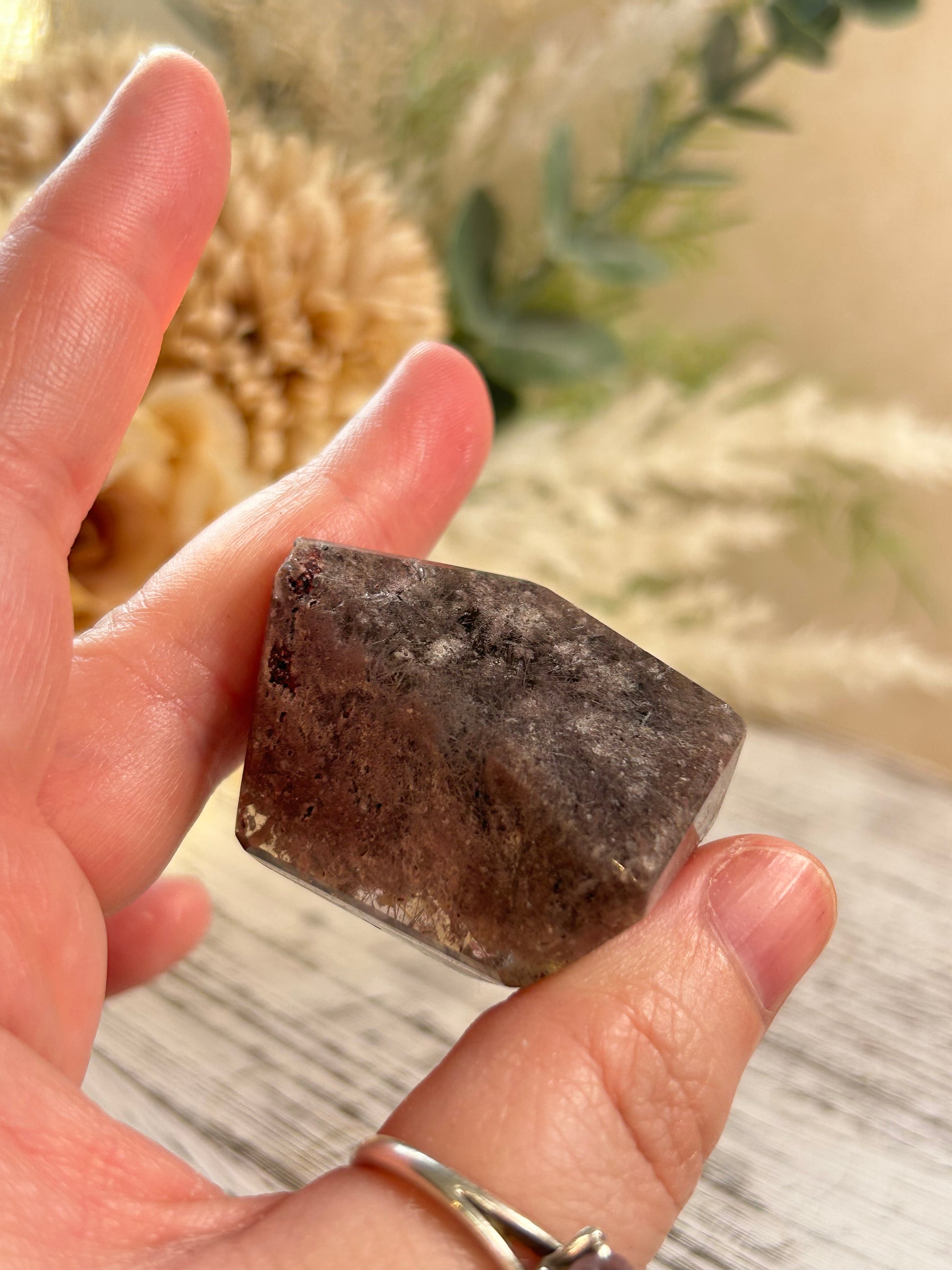 Hand holding a rough stone with a blurred natural background