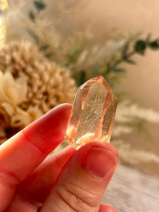 Hand holding a clear crystal with a blurred natural background