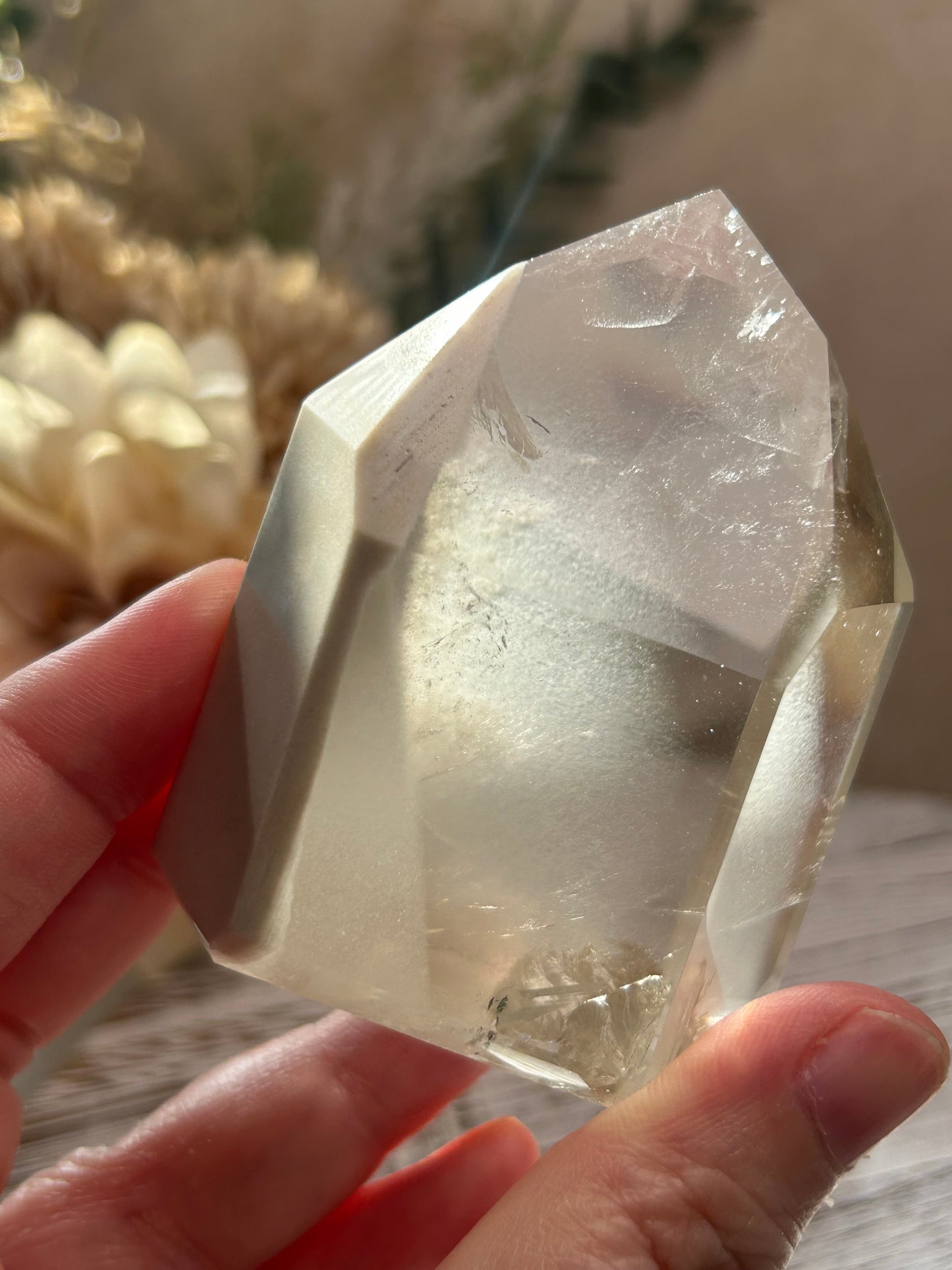 Clear crystal held by a hand with a blurred natural background