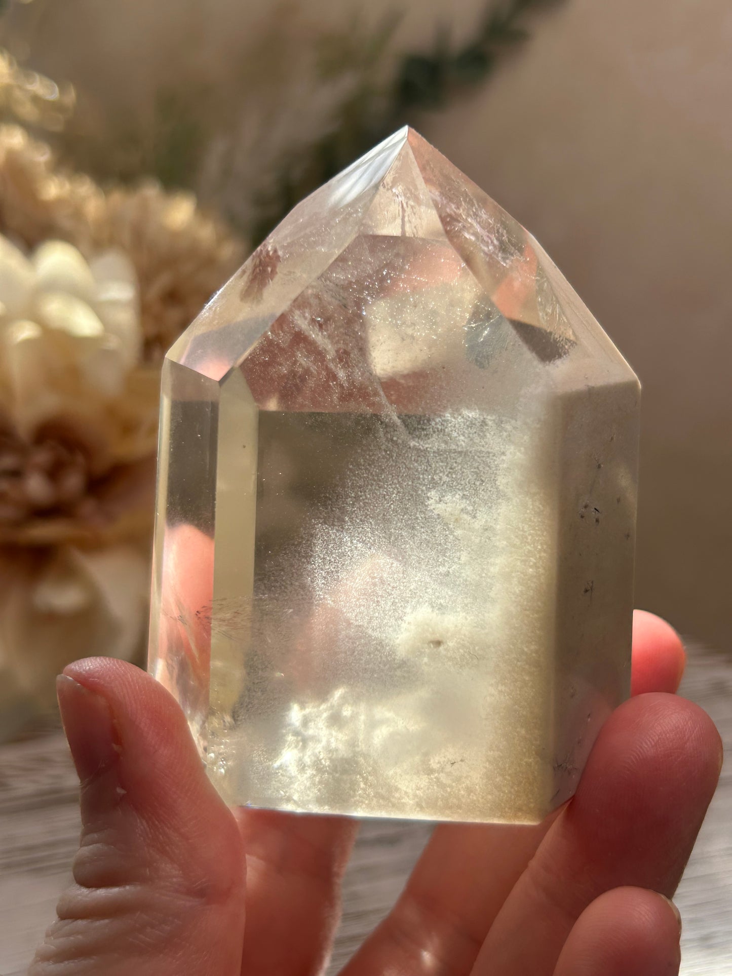 Clear crystal held by a hand with a blurred background