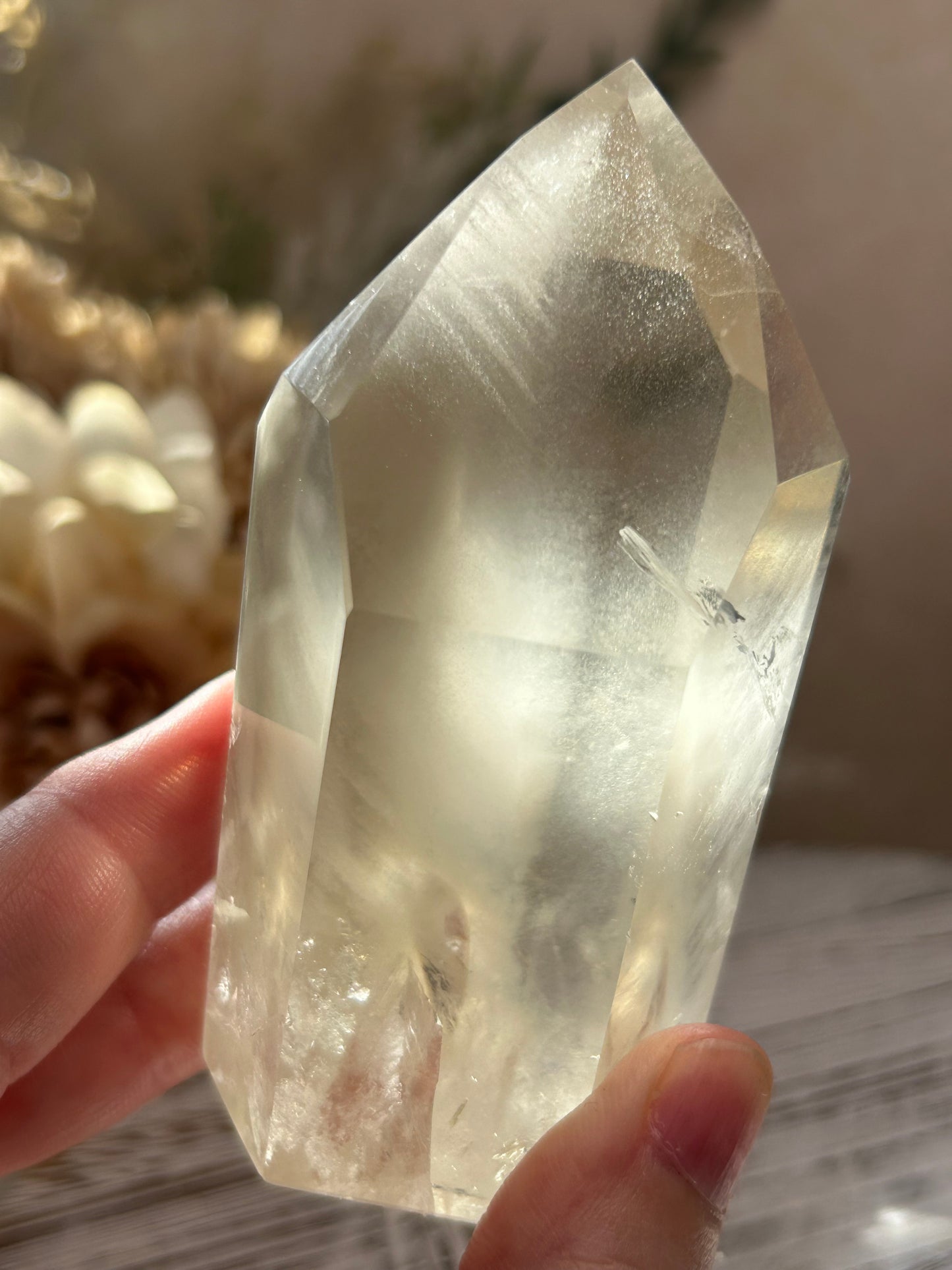 Clear crystal held by a hand with a blurred background