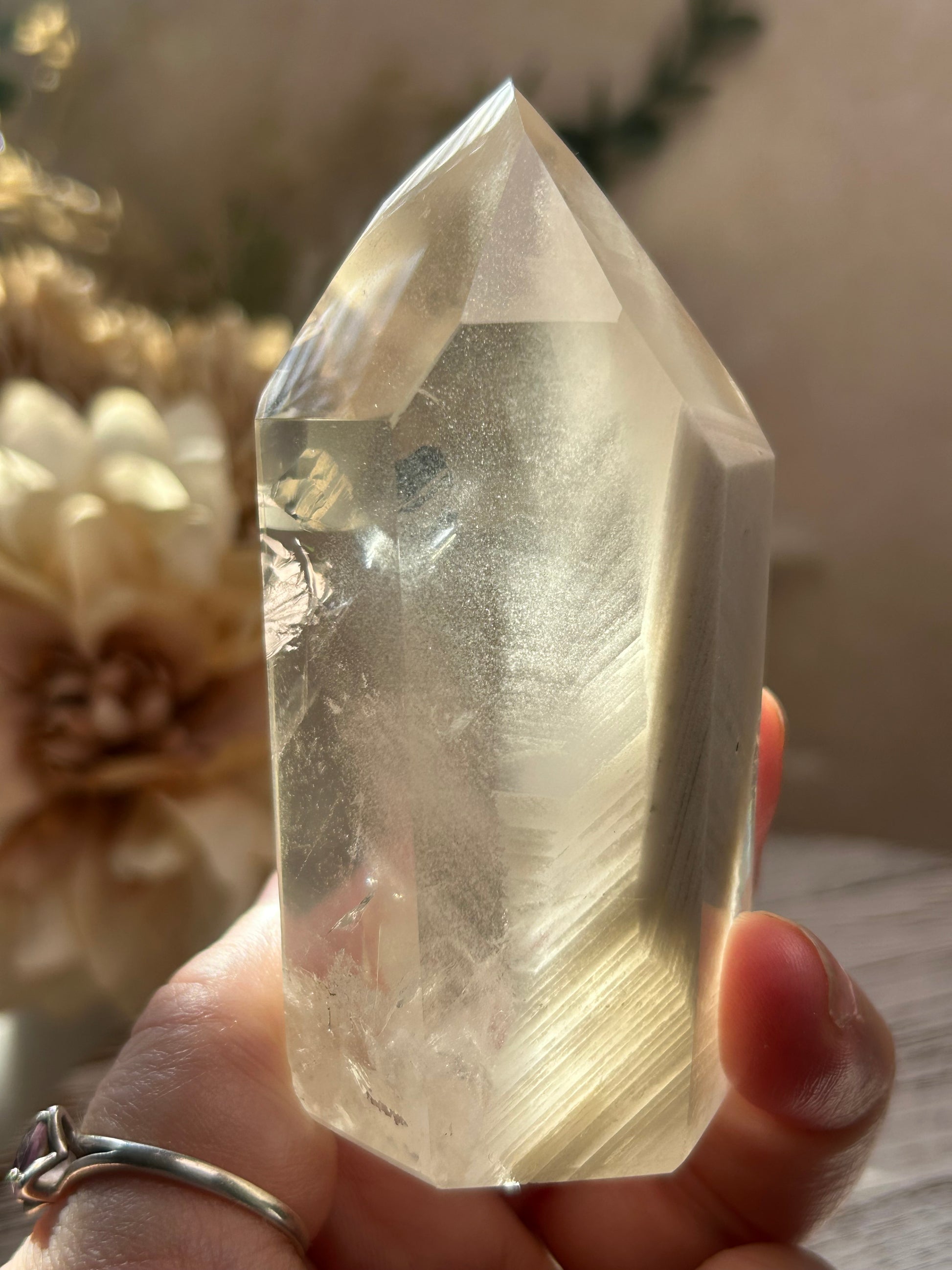 Hand holding a clear crystal with a blurred background