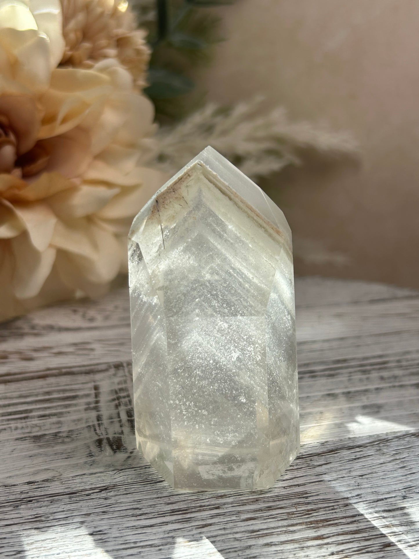 Clear crystal on a wooden surface with flowers in the background