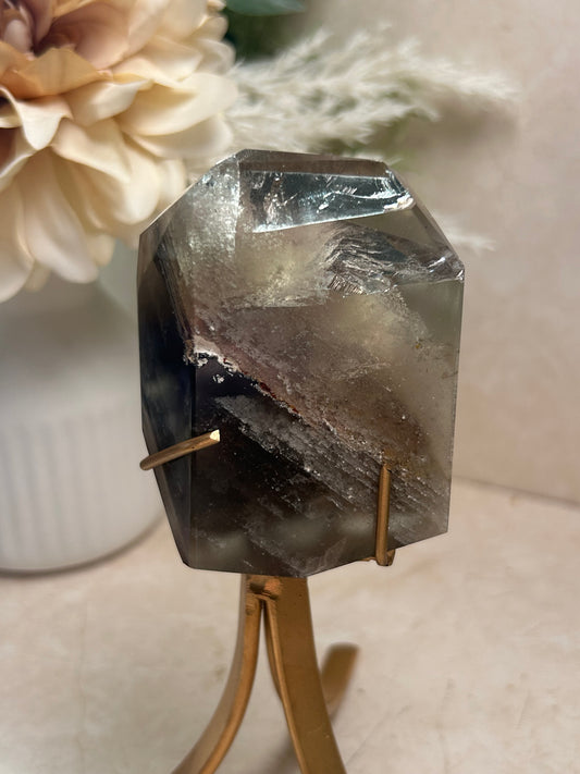 Phantom Quartz crystal specimen mounted on a custom display stand, showcasing visible phantom formations within the Quartz. Collector mineral specimen with unique internal crystal growth patterns.